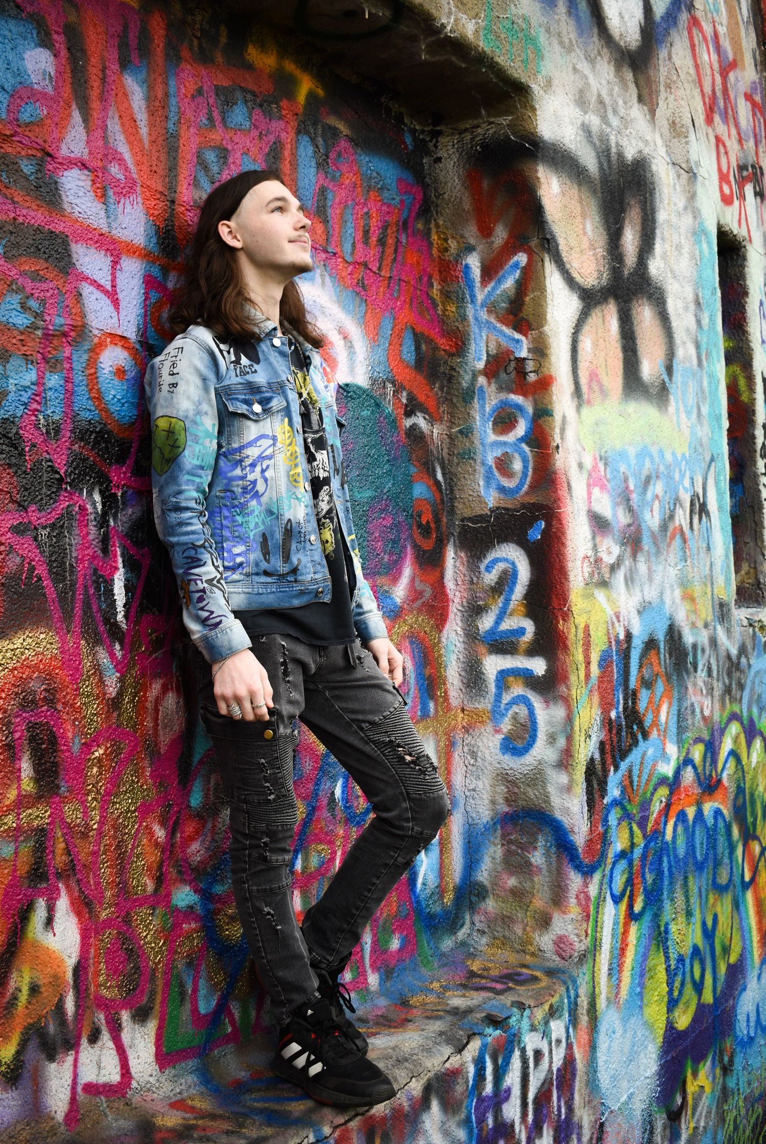 Urban photoshoot against colorful graffiti wall featuring casual denim and dark attire.