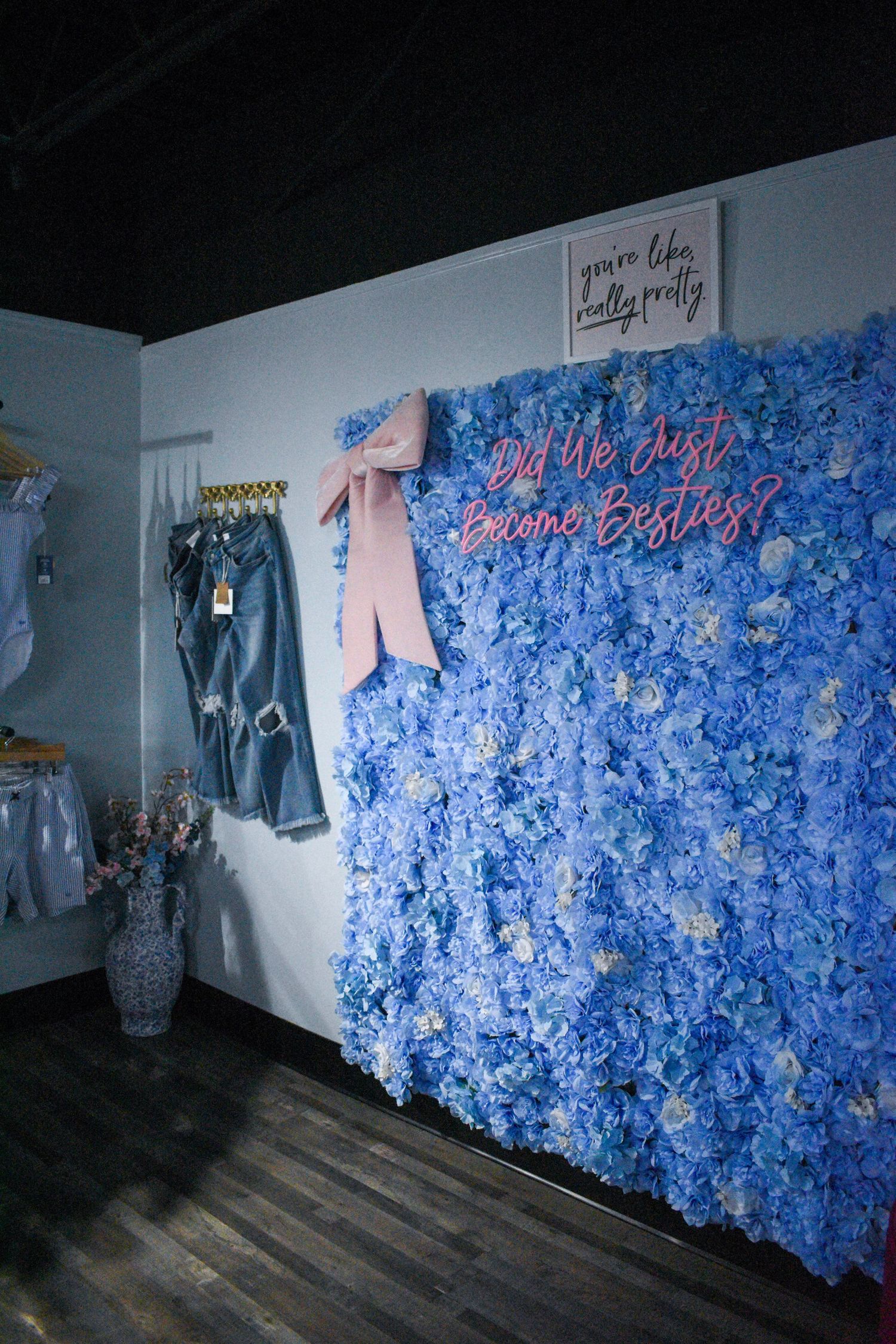 Blue floral wallpaper lines the interior walls of a clothing boutique.