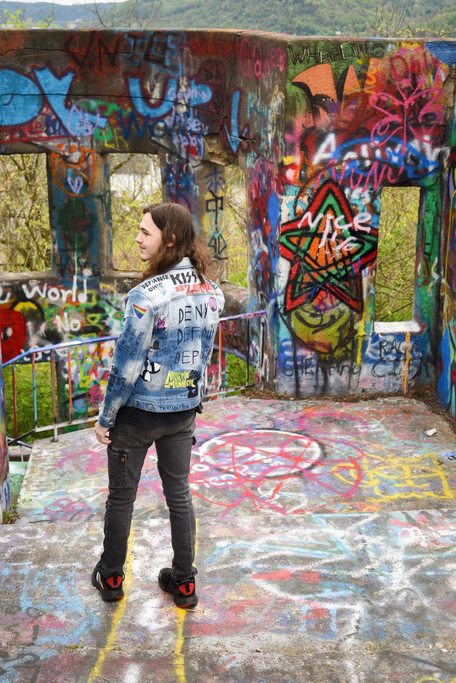 Stylish denim outfit against colorful graffiti backdrop with mountain view.