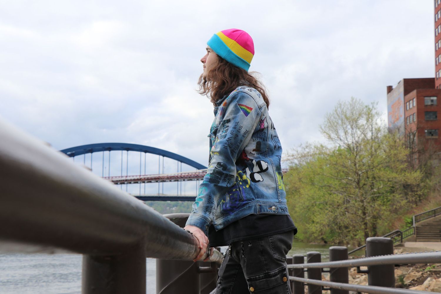 Casual style with colorful beanie overlooking river and bridge.