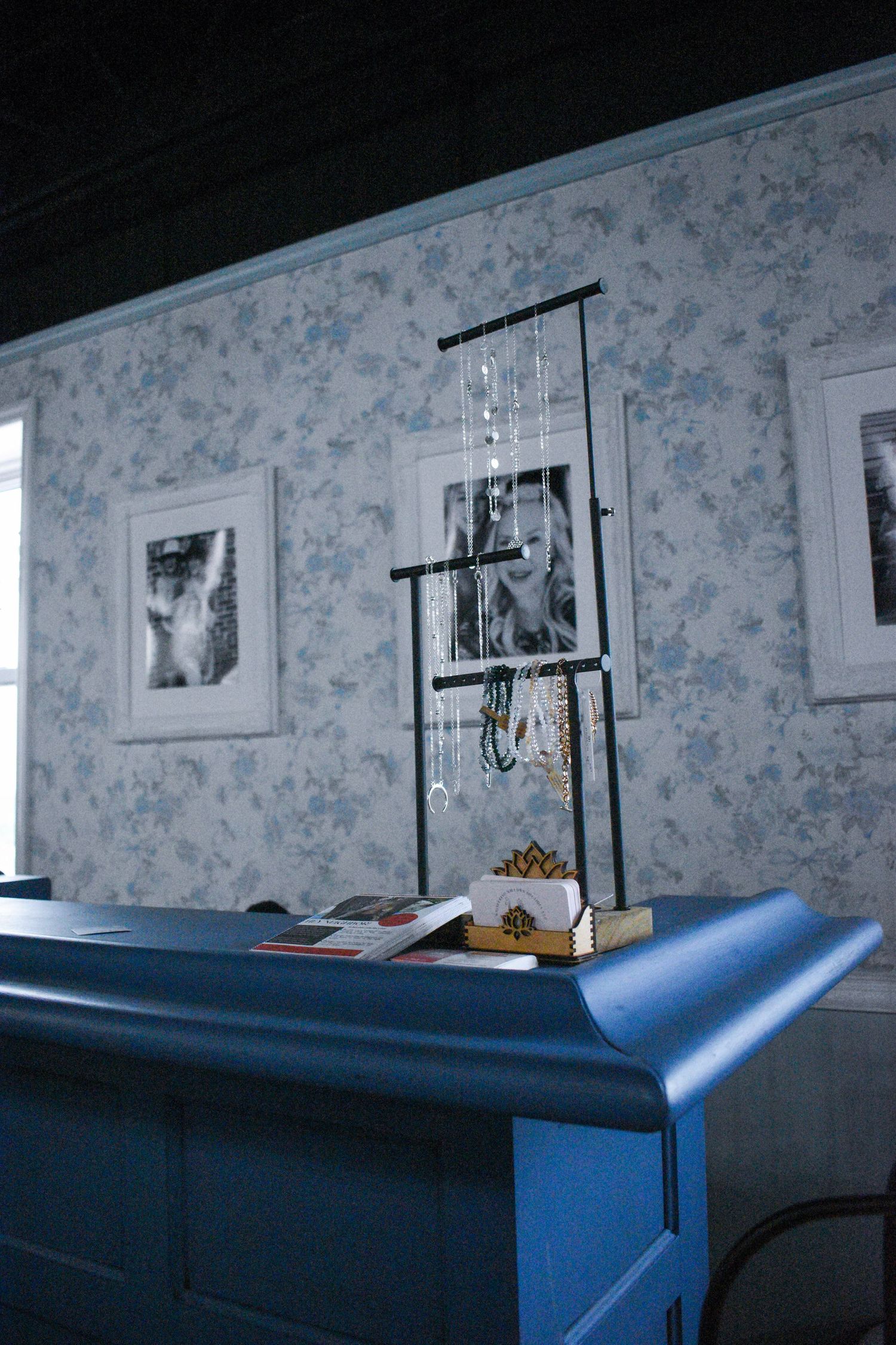 Interior view of boutique with blue floral wallpaper and framed artwork.