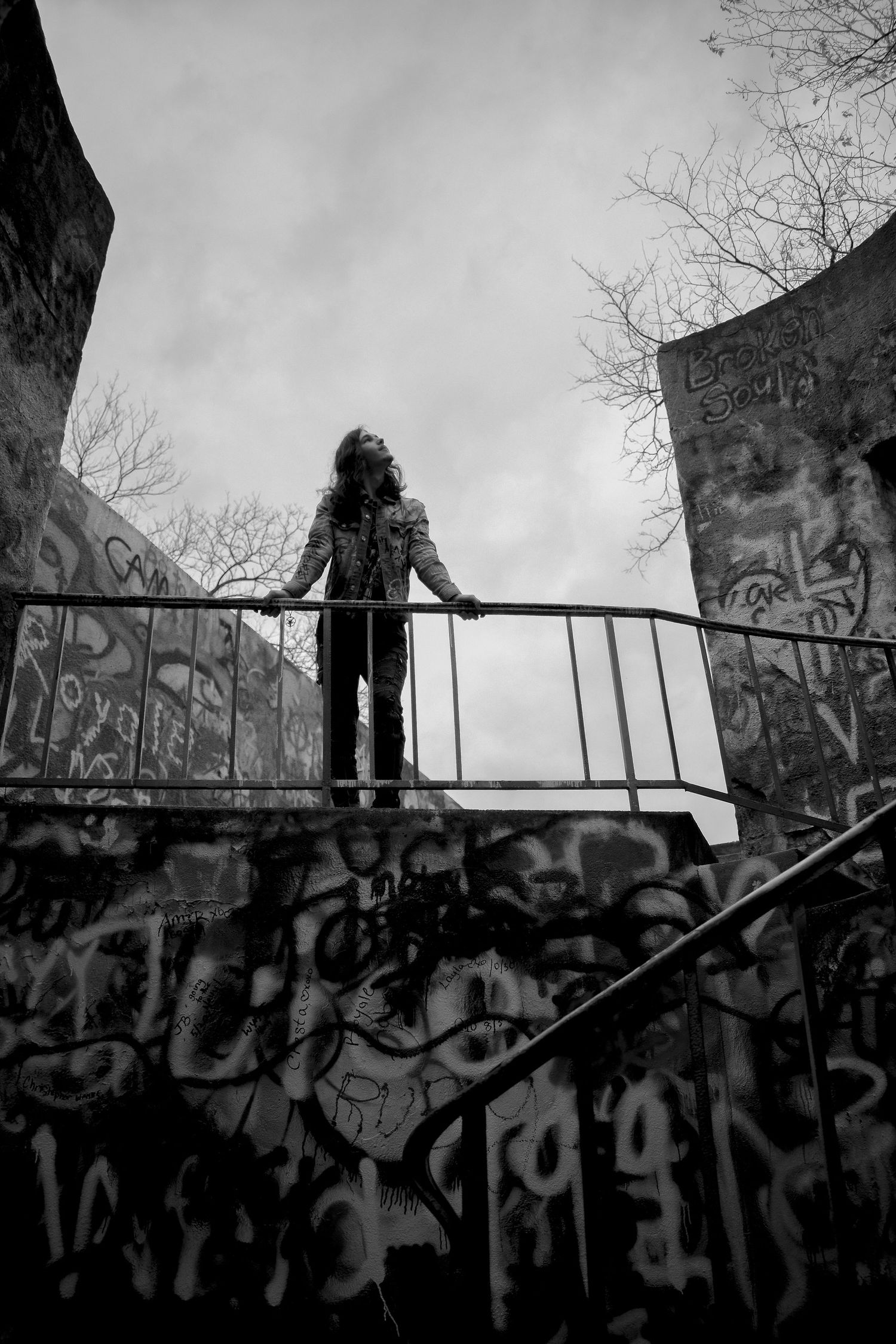 Dramatic black and white shot on graffiti-covered bridge or walkway.