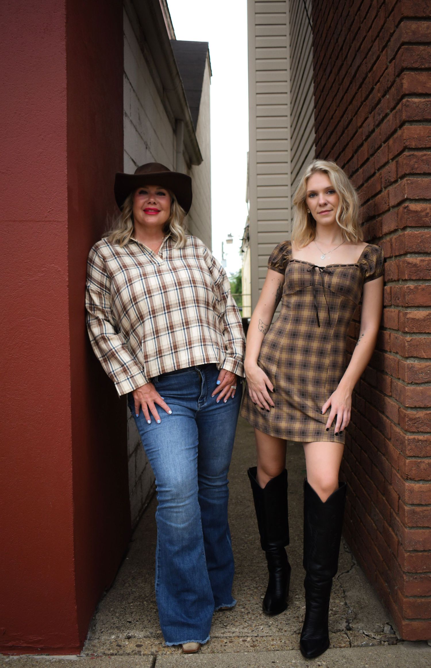 Two people standing in an alleyway wearing western-inspired casual outfits.