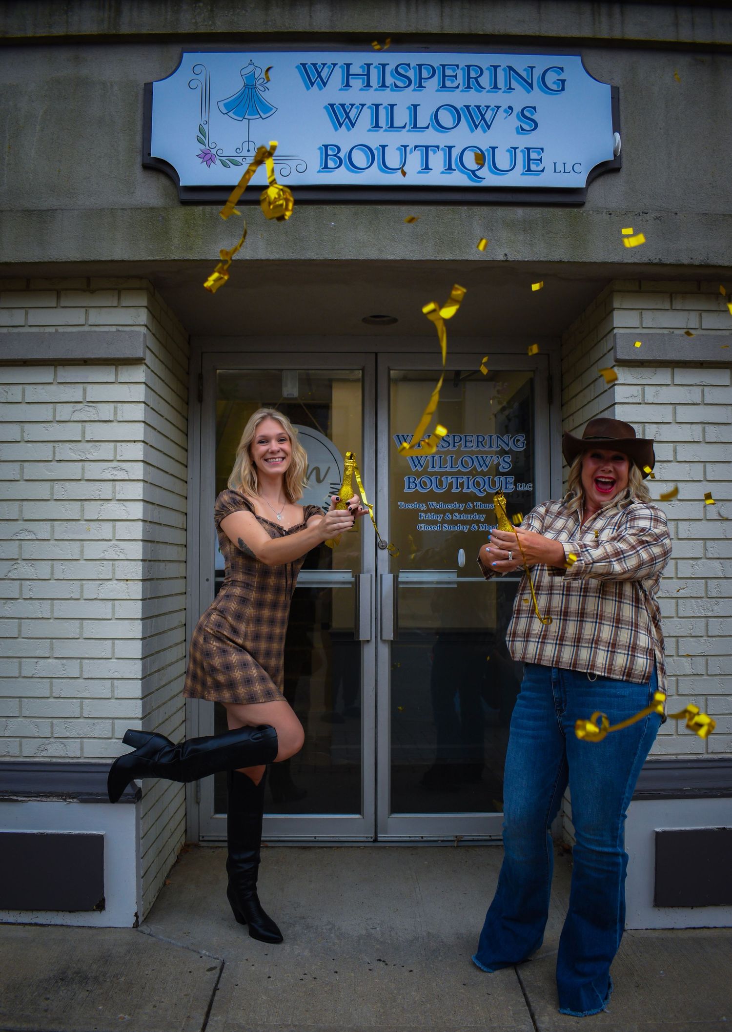 Two people joyfully tossing yellow flowers in front of Whispering Willow's Boutique storefront.