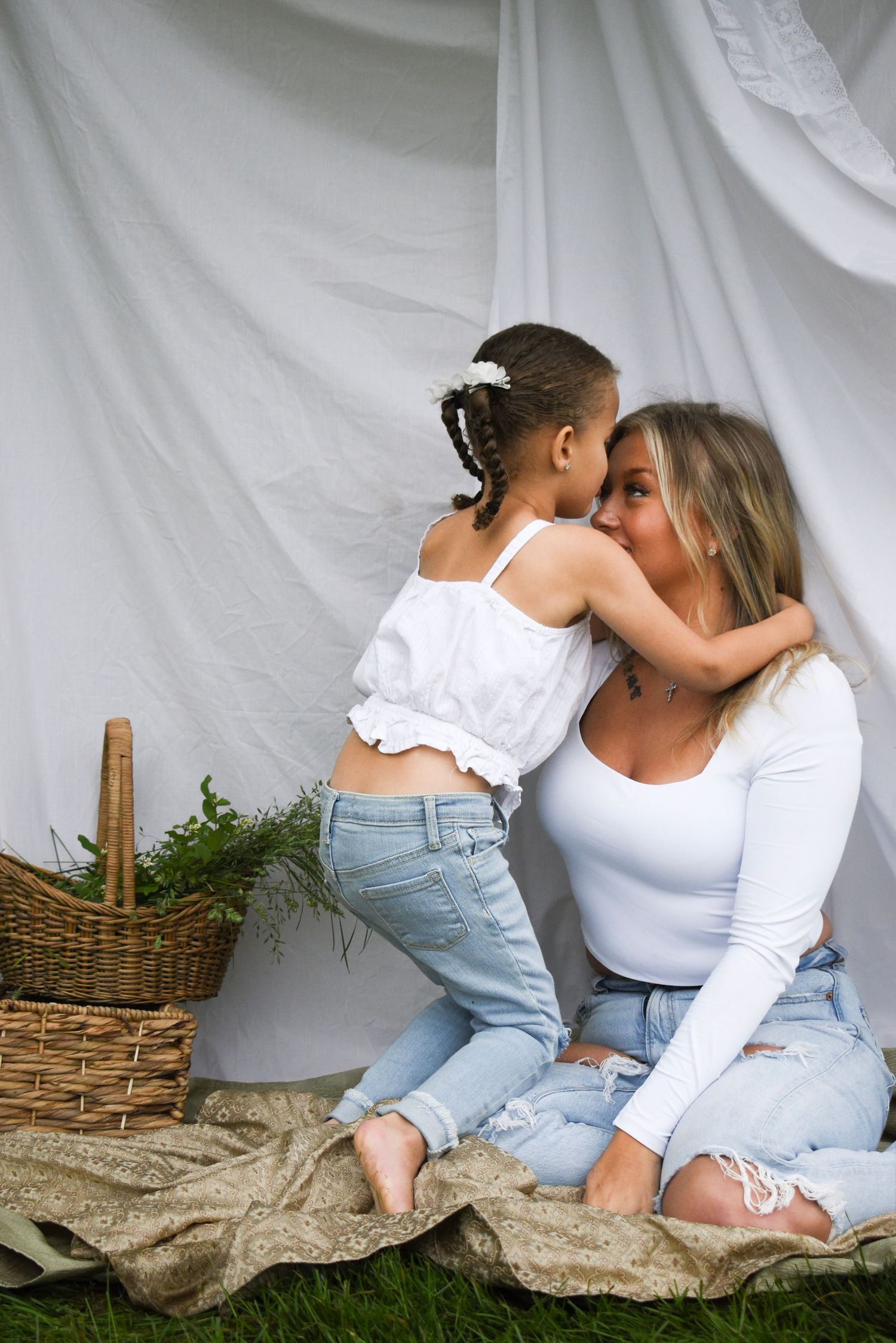 Tender bonding moment on blanket with wicker basket and white backdrop.