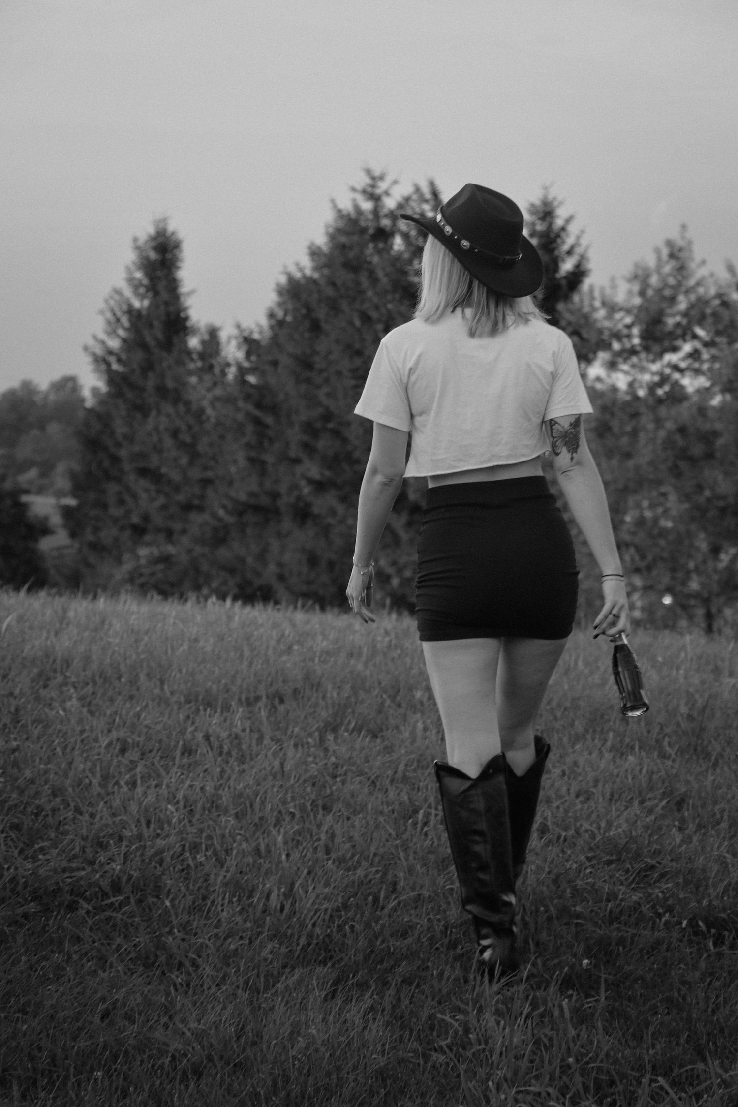 Figure in black shorts and boots standing in a grassy meadow during golden hour.