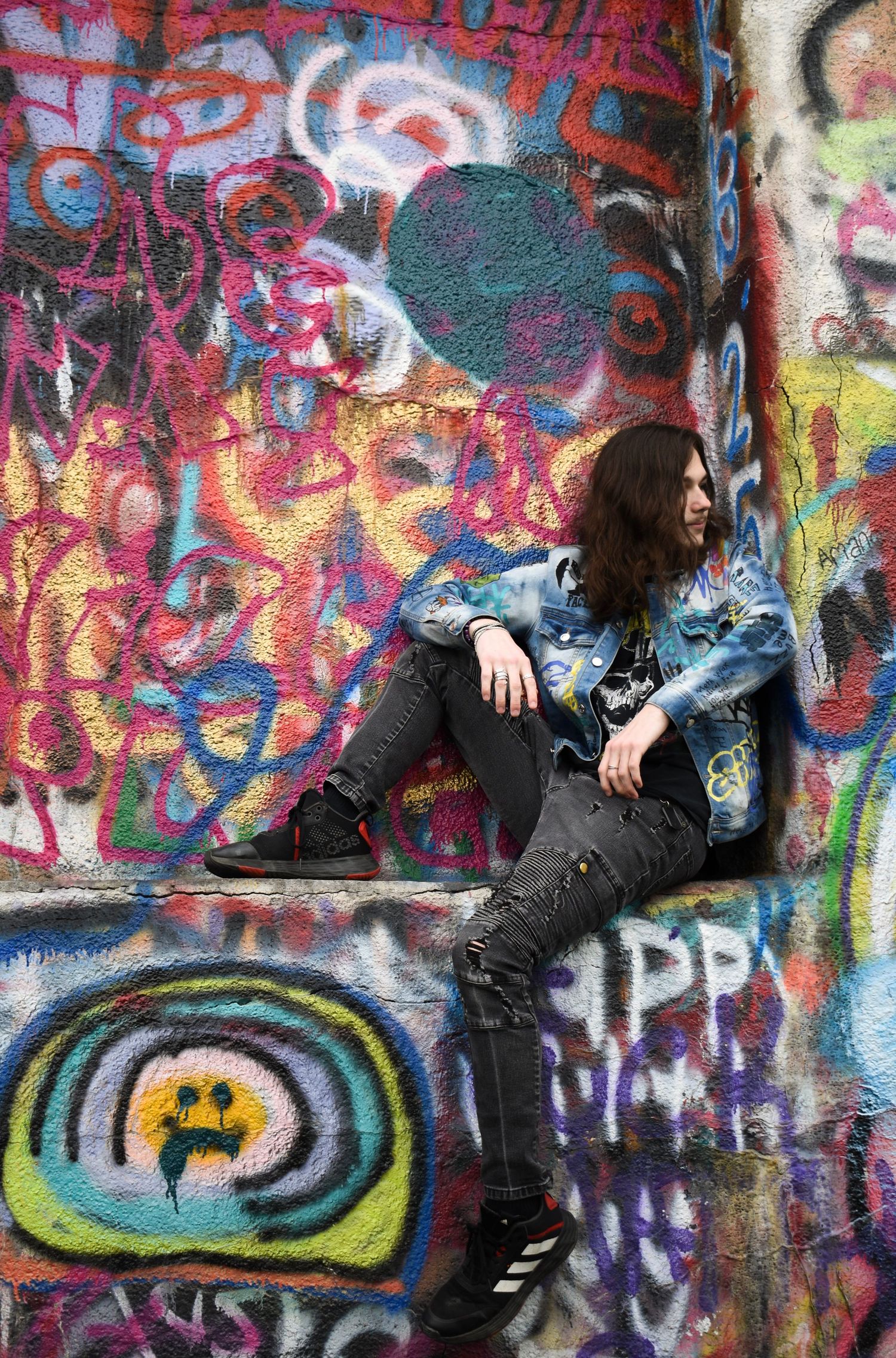 Edgy urban portrait against vibrant graffiti wall with circular designs.