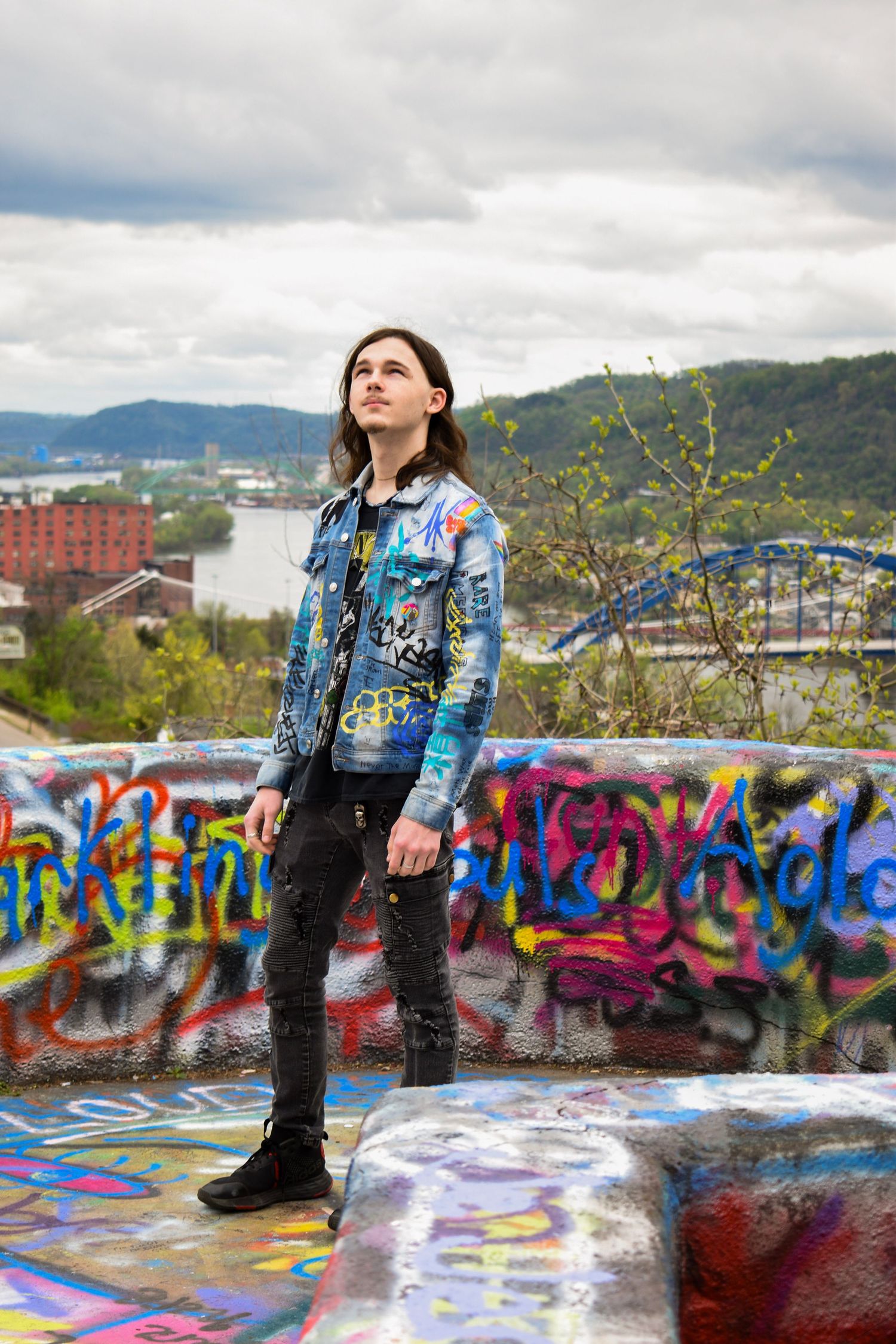 Scenic overlook with graffiti wall and cloudy mountain landscape in background.