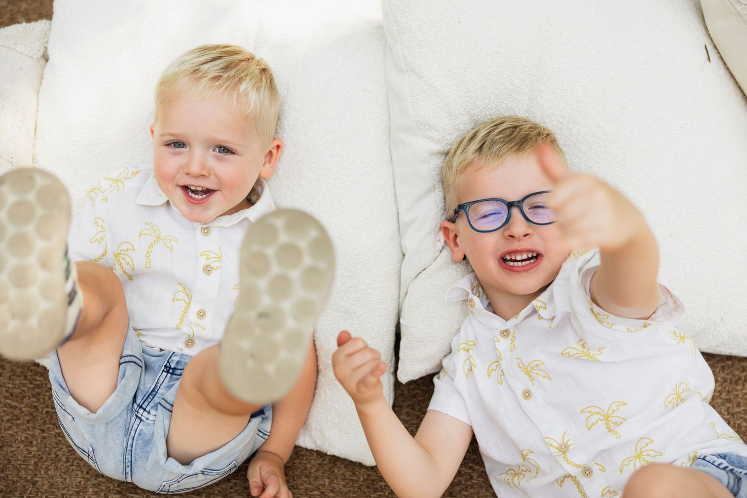 Two children laying on white cushions showing off their anti-slip socks while laughing. Shellharbour
