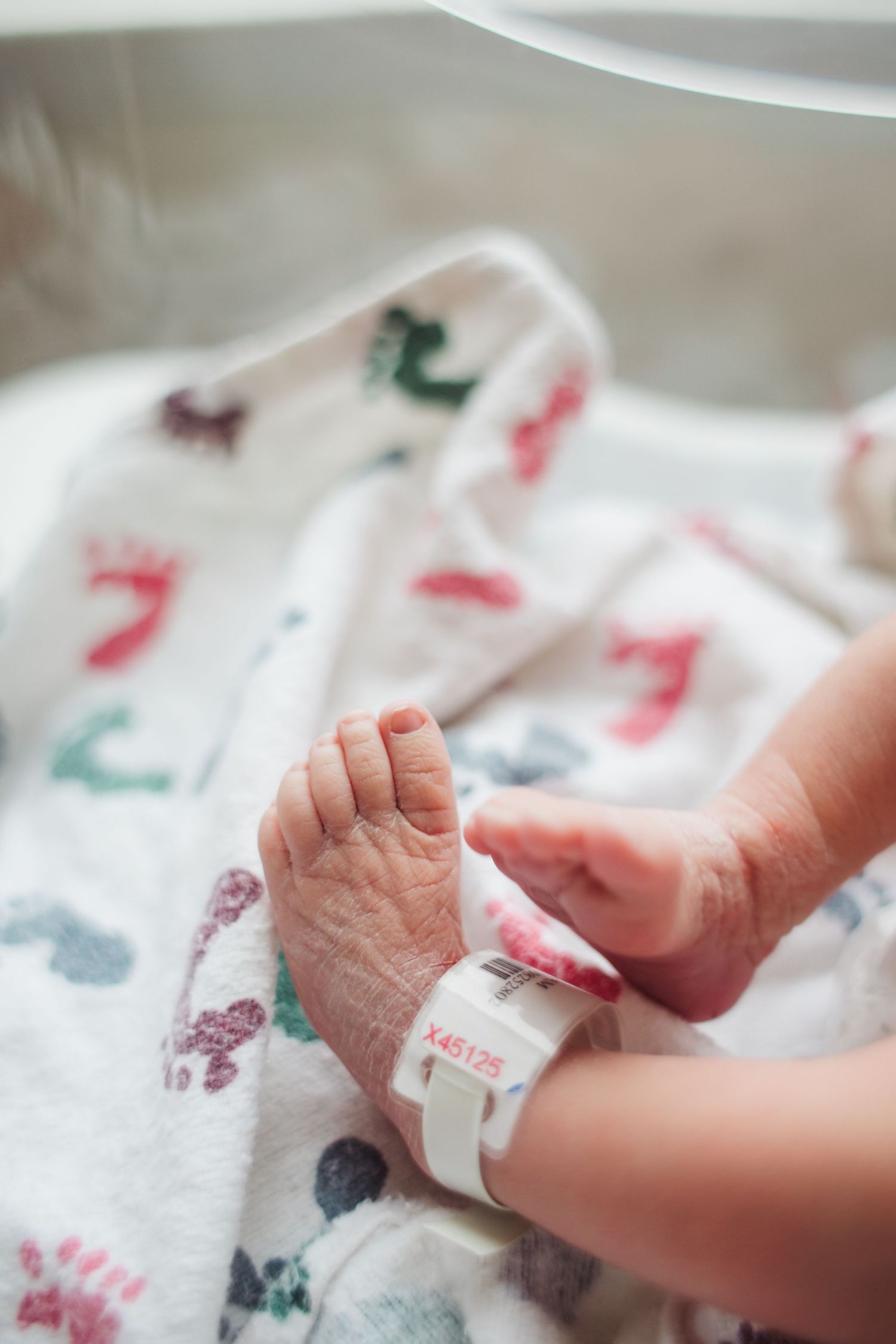 A collection of images showing tiny baby hands and feet resting on a white blanket with colorful pattern details.