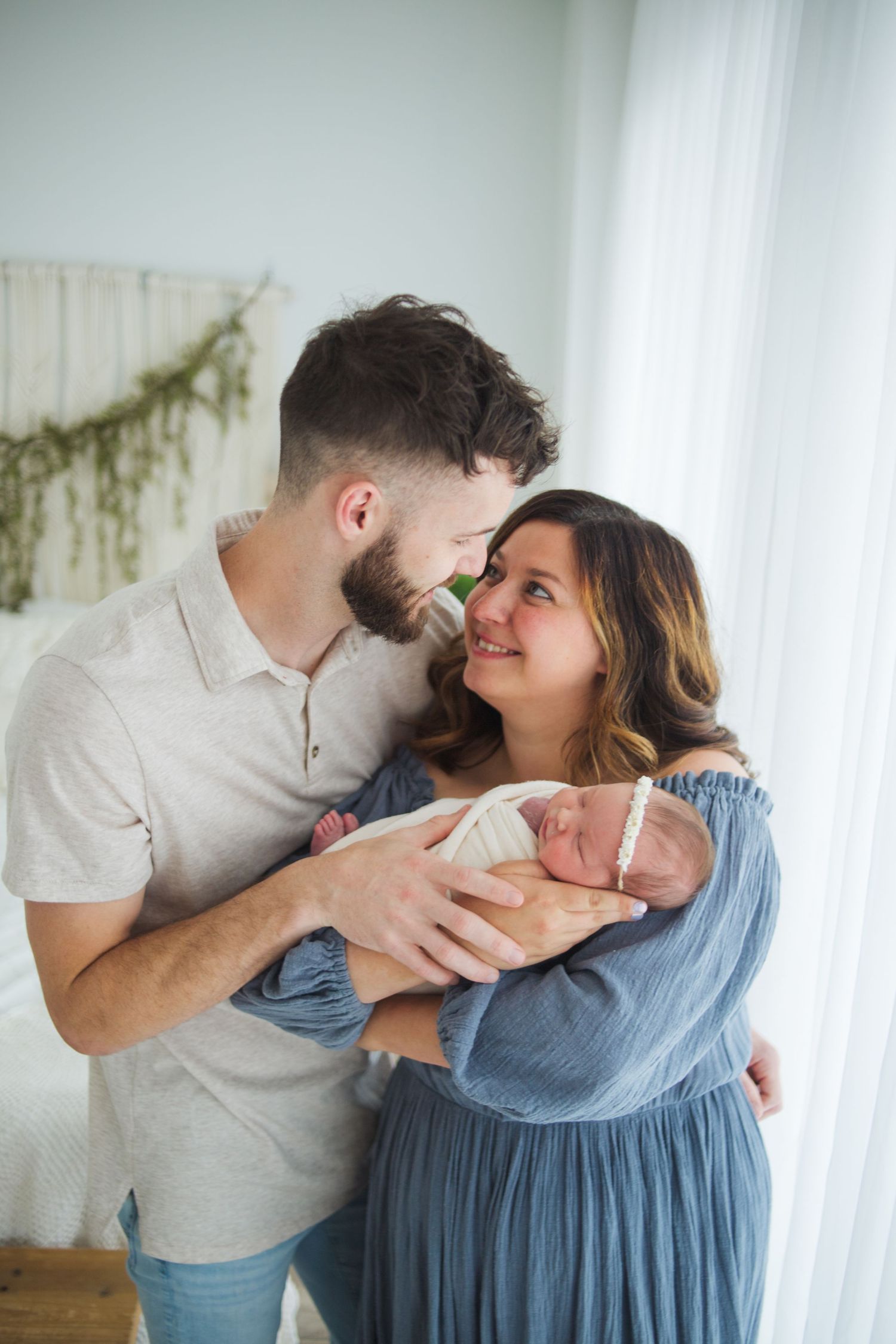 Springfield MO newborn photographer – parents gently holding baby during lifestyle session by Fairchild Photo Co