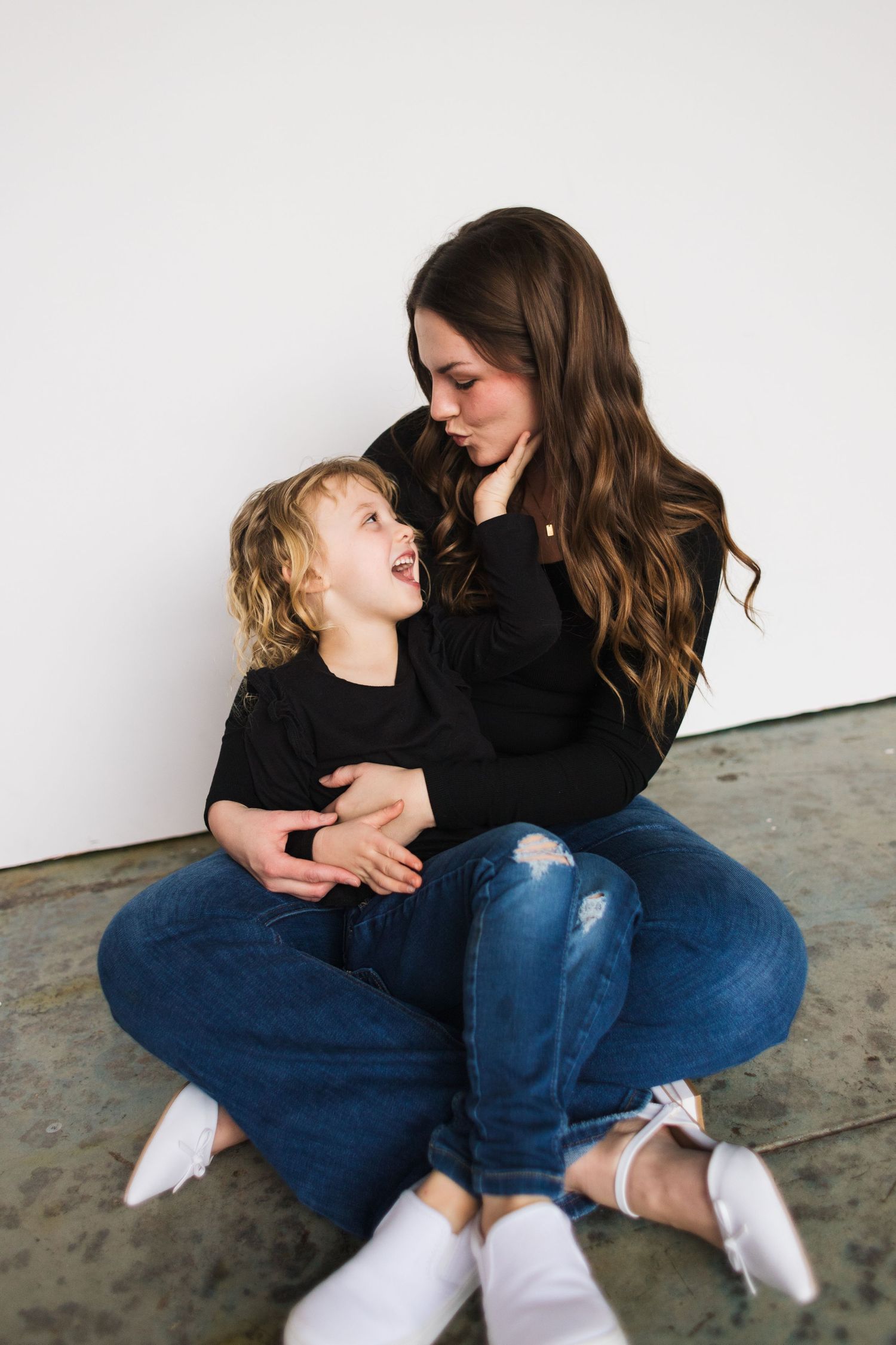 Intimate moment between parent and child sitting on concrete floor.