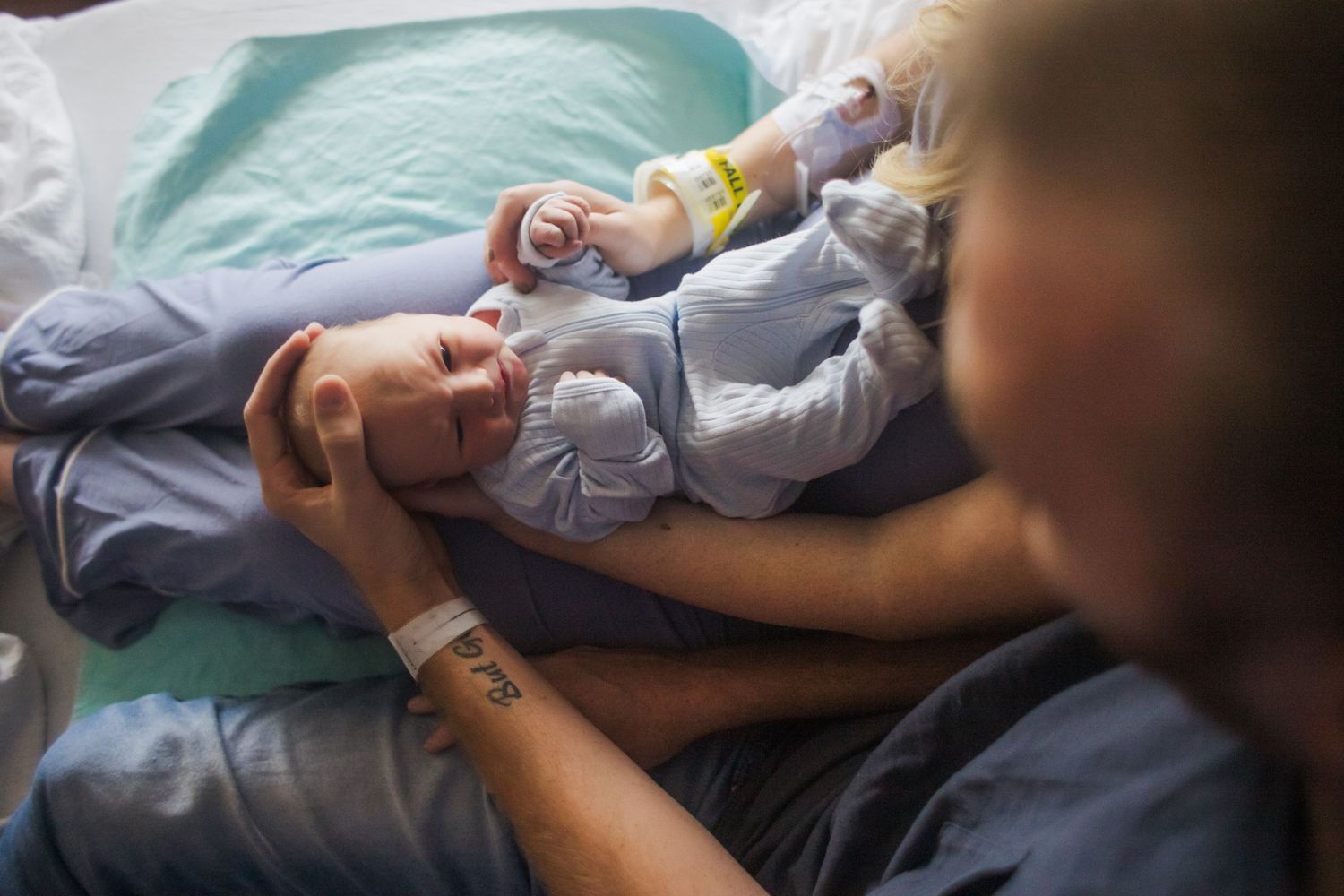 A baby sleeps peacefully in a hospital bassinet while wearing a light blue outfit.