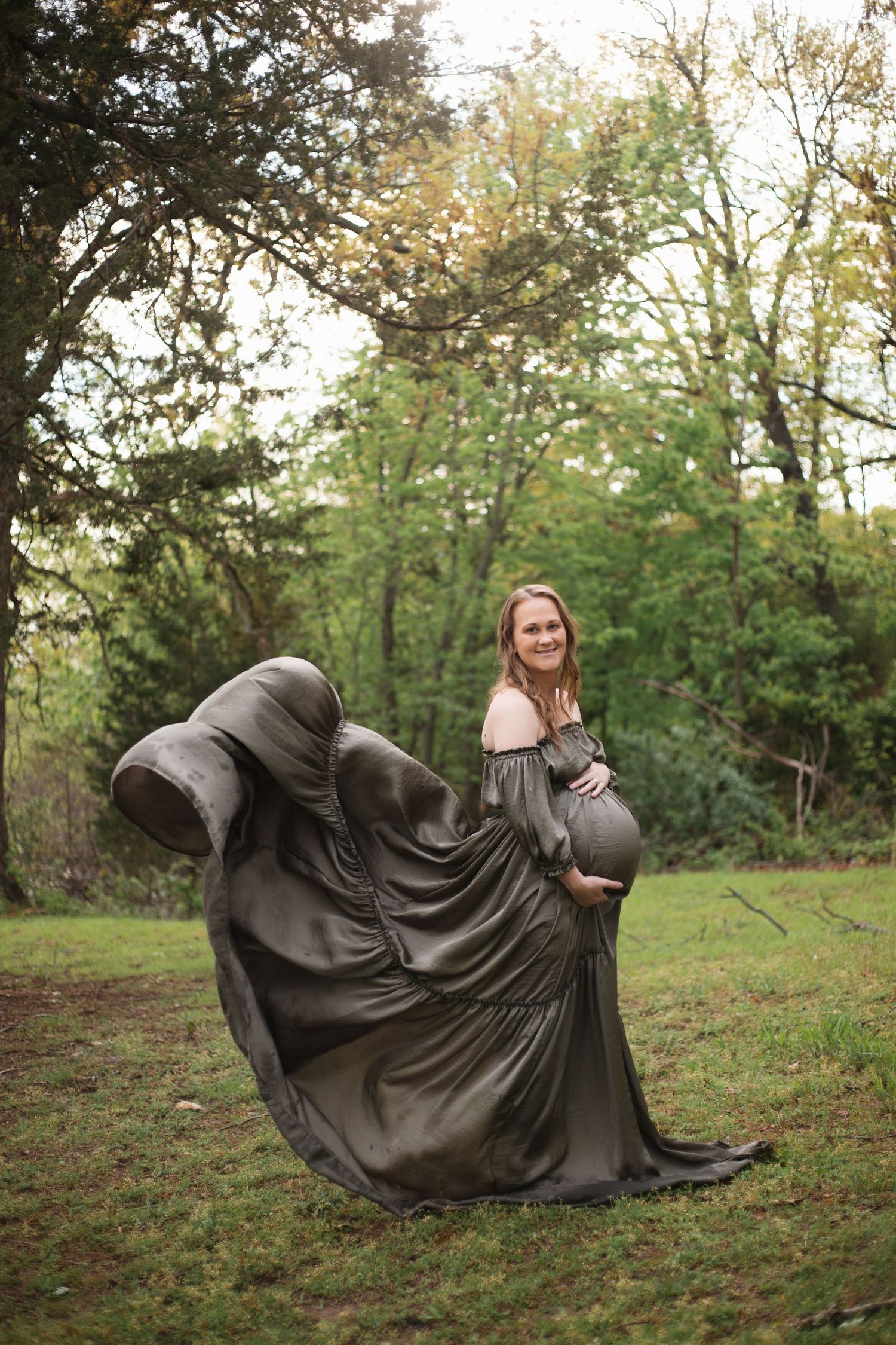 Series of dramatic poses in a flowing black dress on grassy field at sunset.