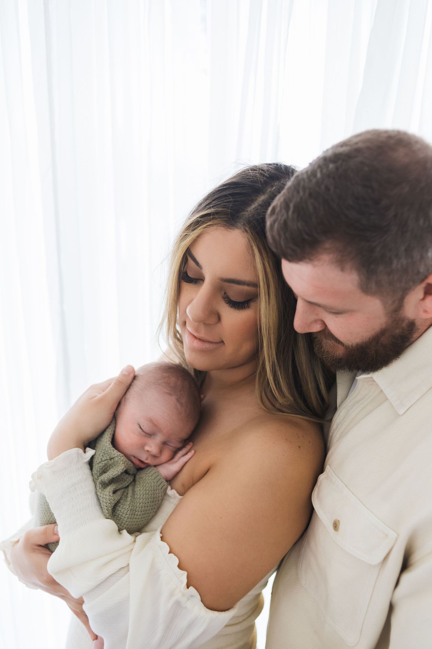 Mom and dad holding newborn baby tenderly – lifestyle newborn photography Springfield MO by Fairchild Photo Co