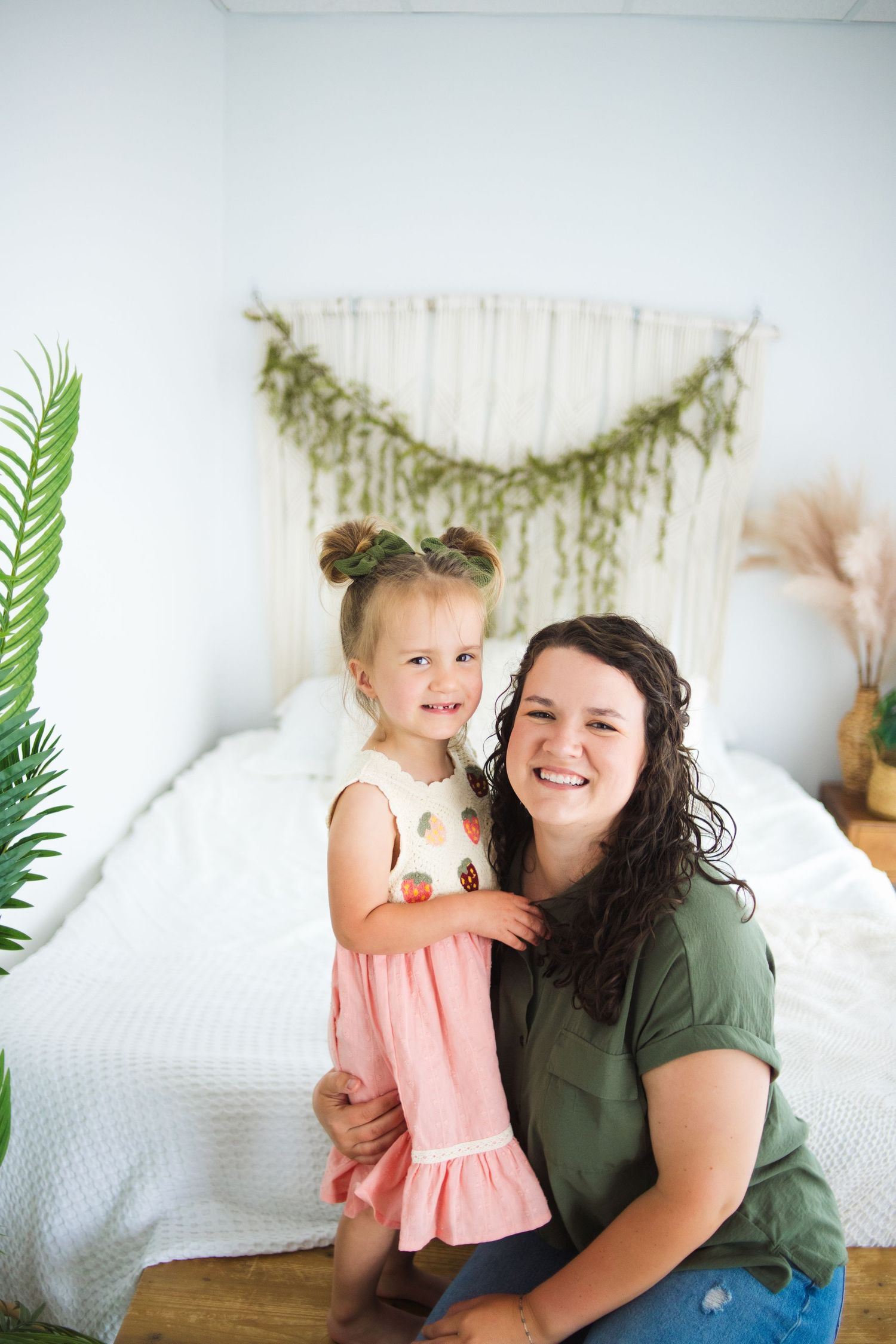 A heartwarming indoor family portrait with decorative greenery and macrame wall hanging.