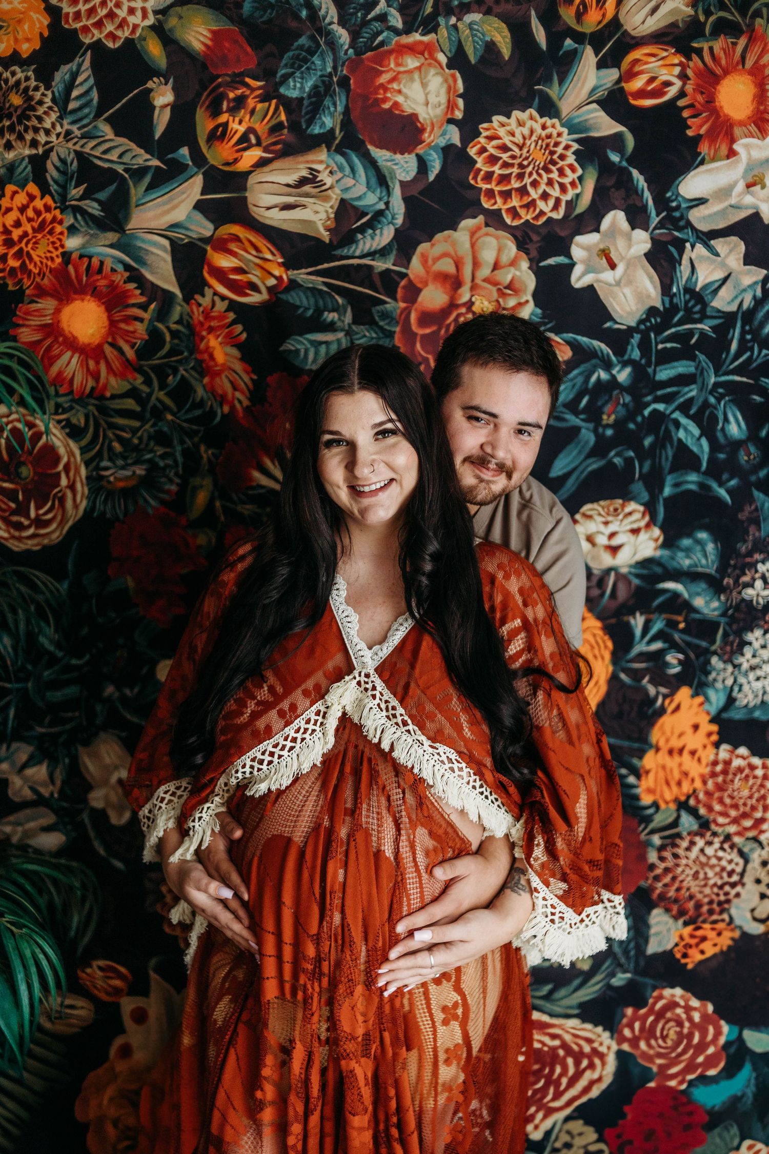 Maternity photo with bohemian dress against floral backdrop.
