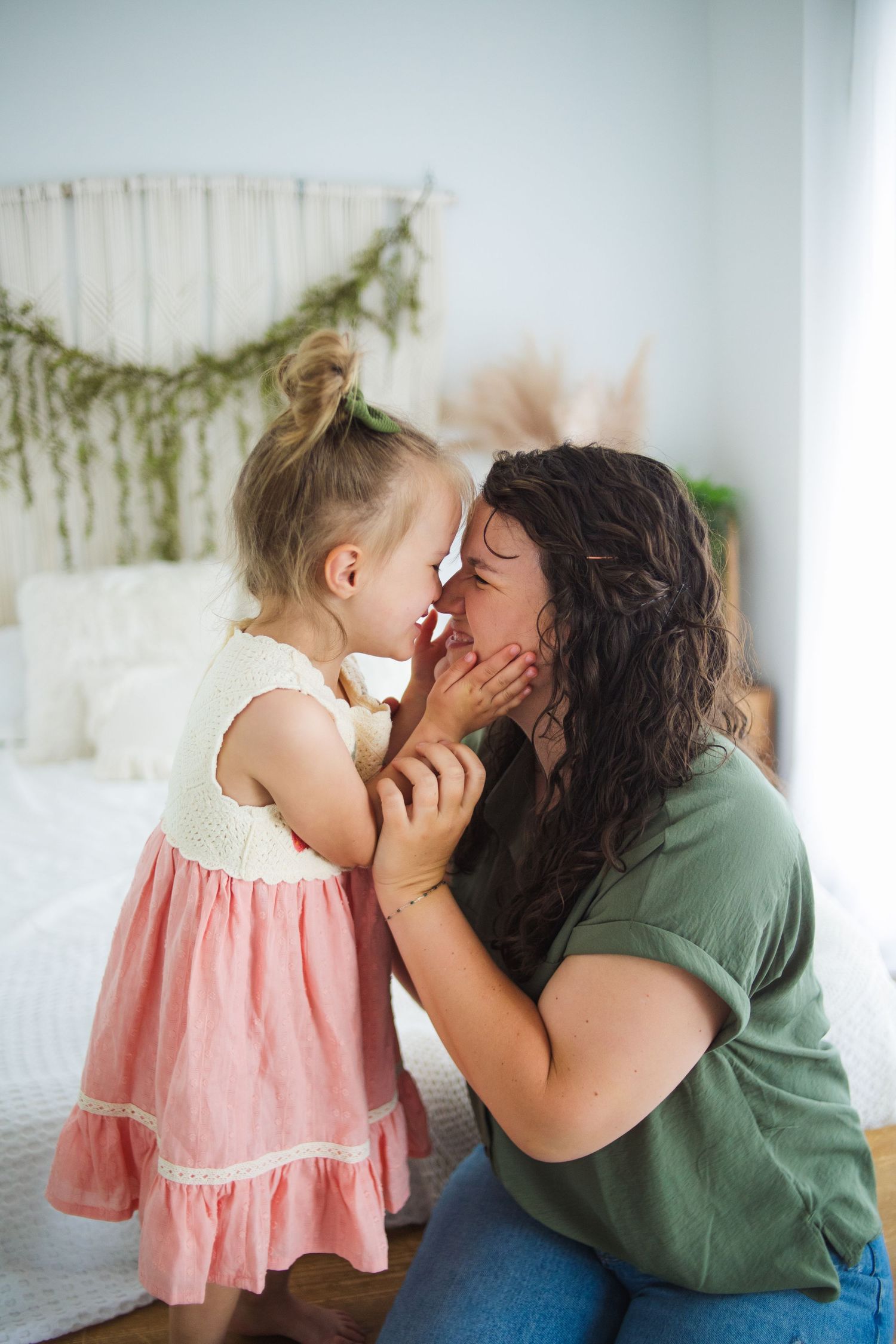 Sweet candid moment captured in sequence showing tender interaction on white bedding with soft pink dress details.
