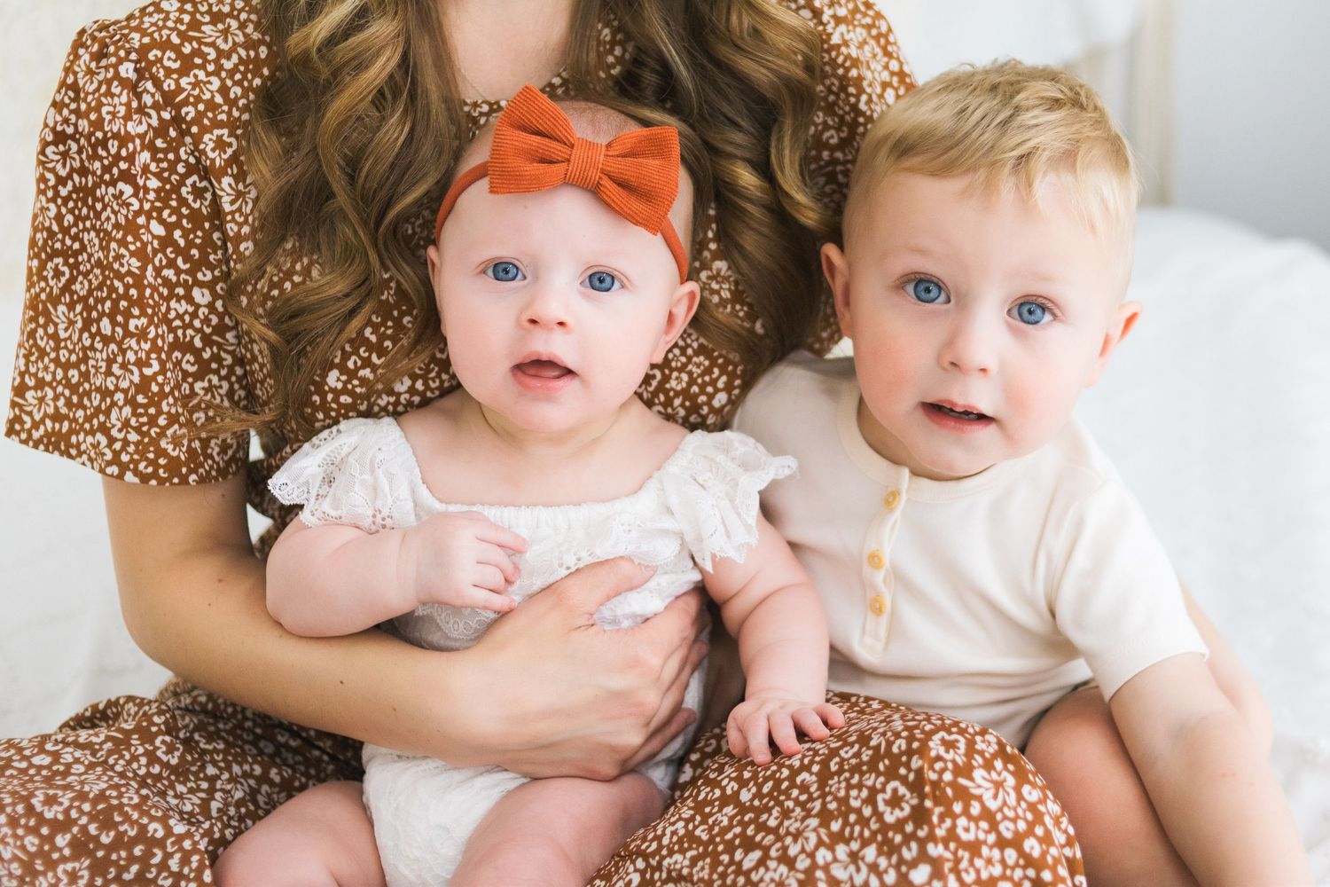 Loving family portrait featuring small children in coordinating outfits with orange accents.