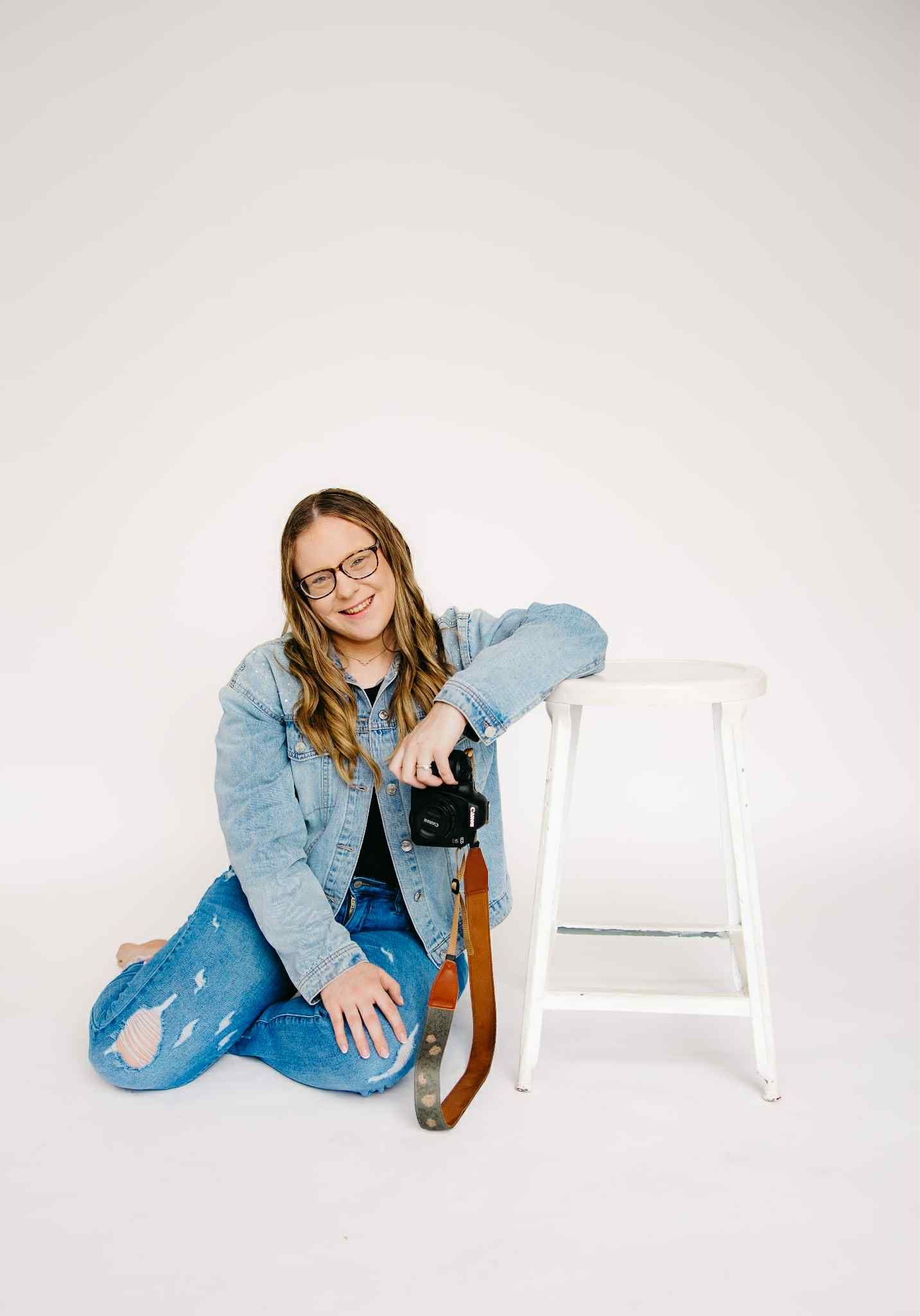 owner of Fairchild Photo Co., posing casually in a light blue denim jacket against a white backdrop, representing contacting and booking.