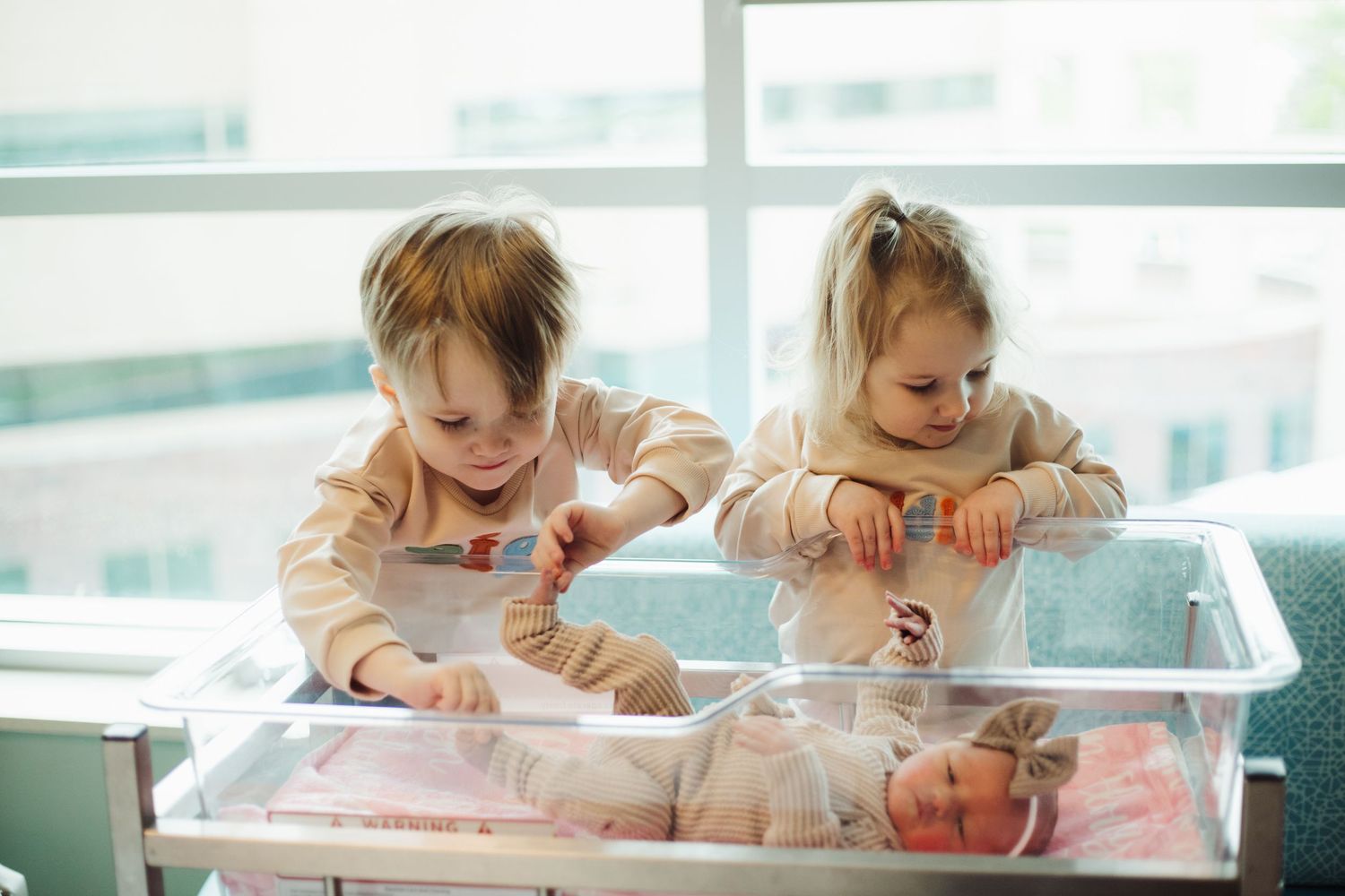 Children explore and learn at a sensory table filled with water and interactive materials by a bright window.