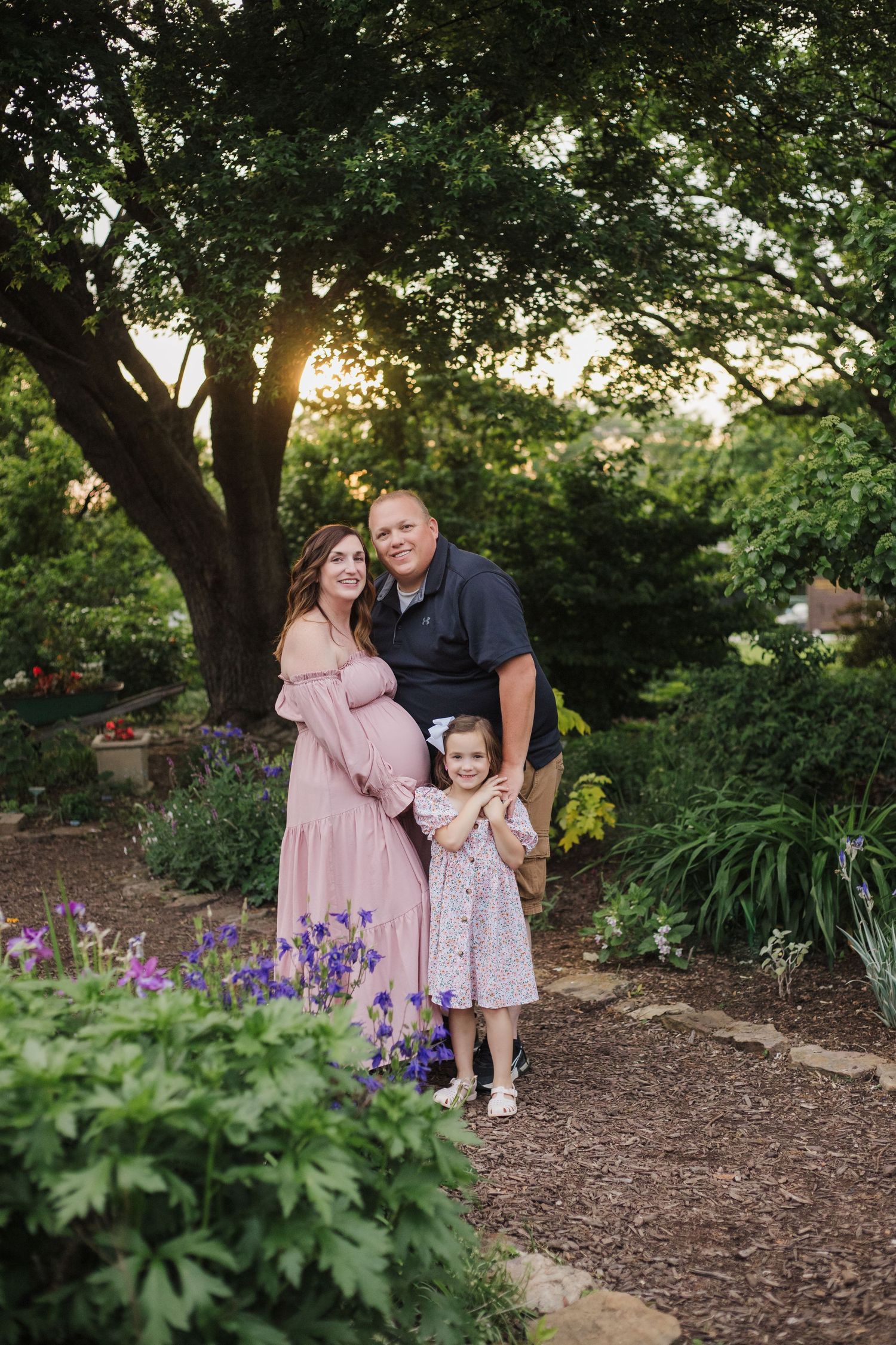 Family photo session in garden with mulched paths and purple iris flowers.