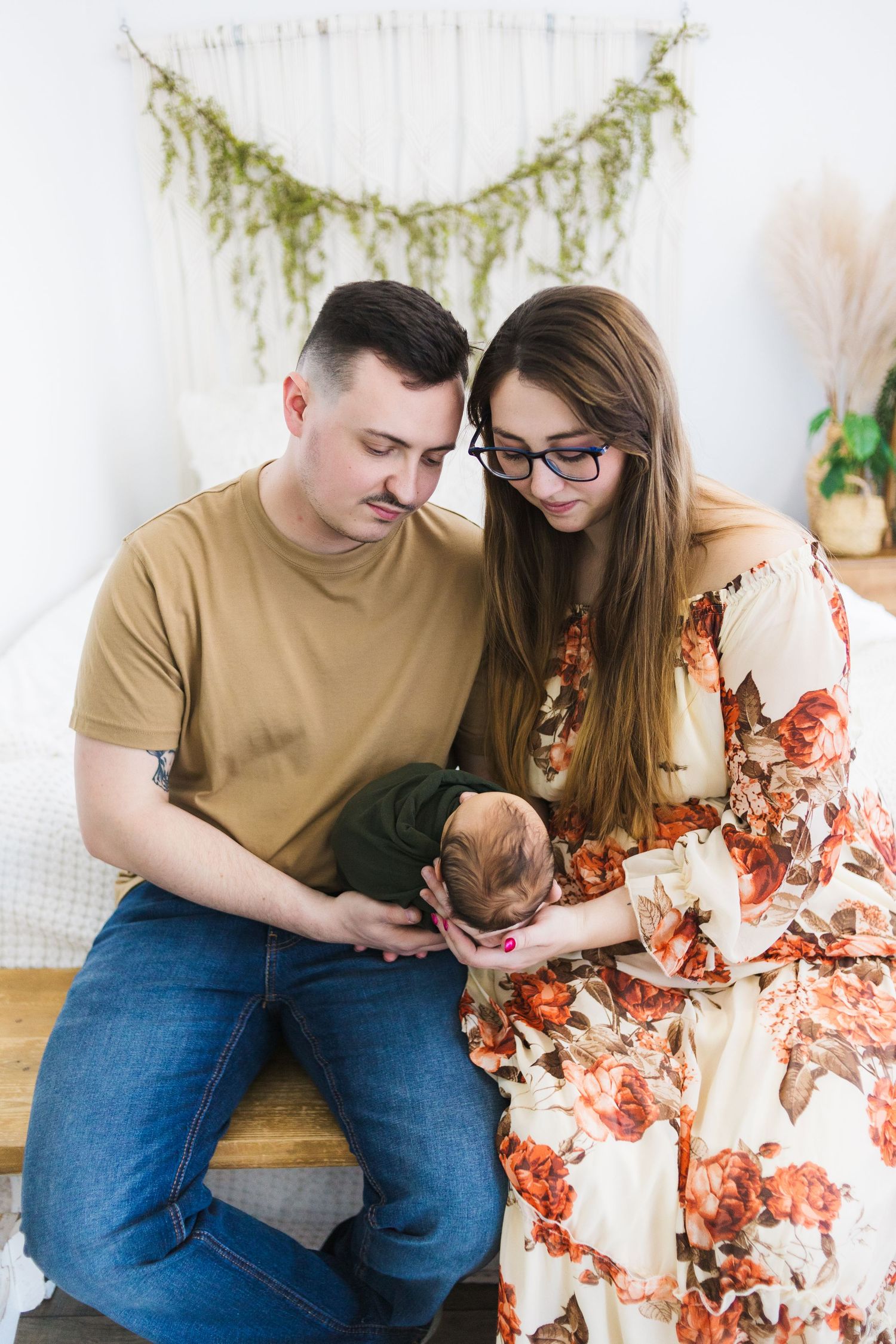 Intimate indoor maternity photo with white shiplap wall and hanging greenery garland.