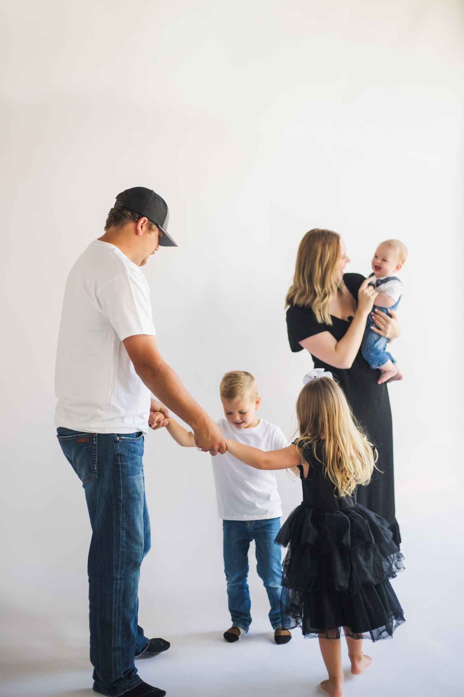Family having fun together in a minimalist white studio setting in casual clothing.