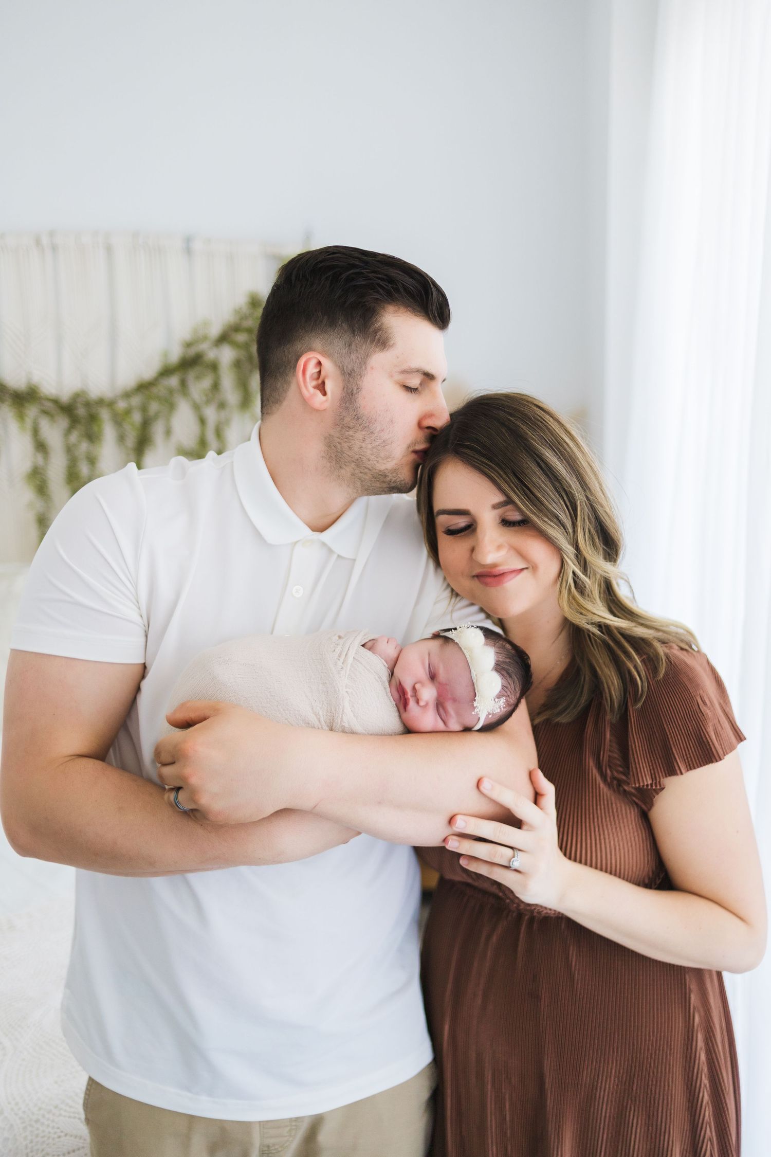 Lifestyle newborn session Springfield MO – parents cuddling newborn in warm neutral tones