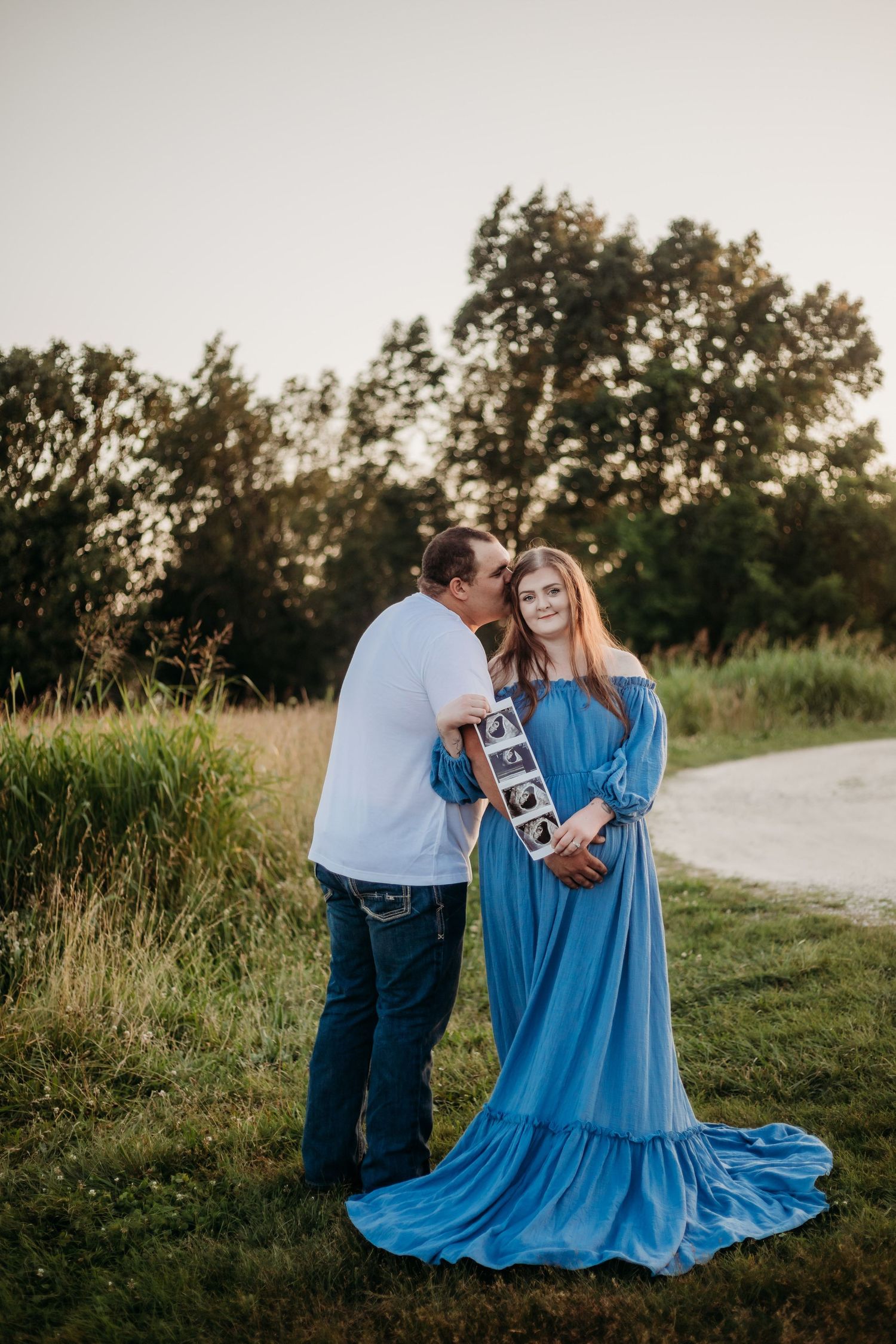 Flowing blue dress photographed in outdoor natural setting during sunset.