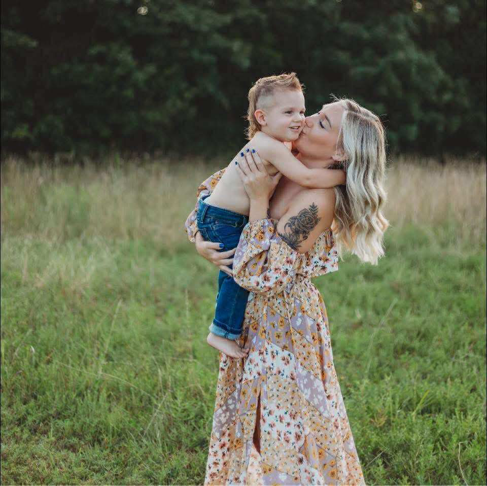 A sweet moment captured in a grassy field on a summer day showing affection.