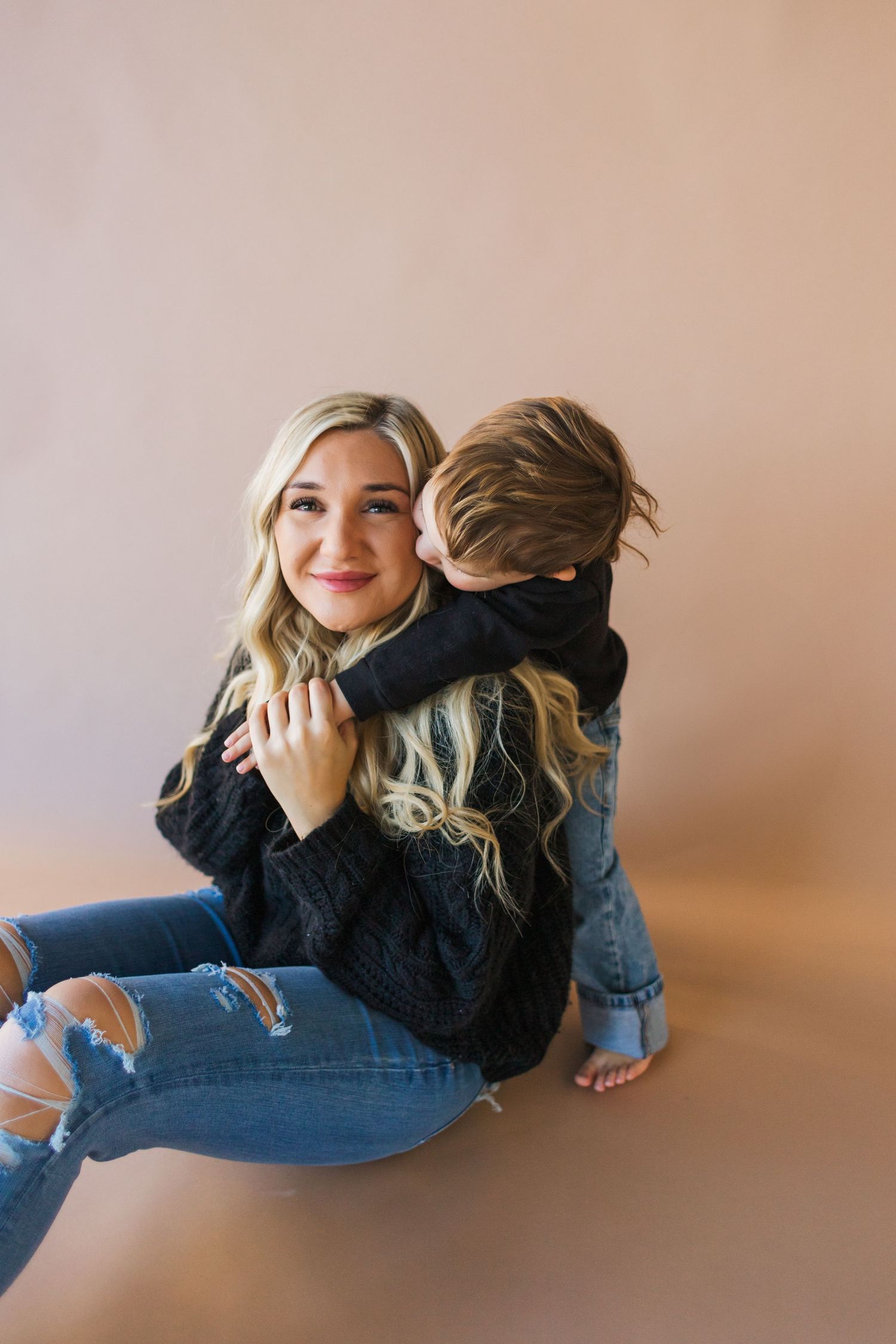 Mother and child share intimate moment while laying on studio floor.
