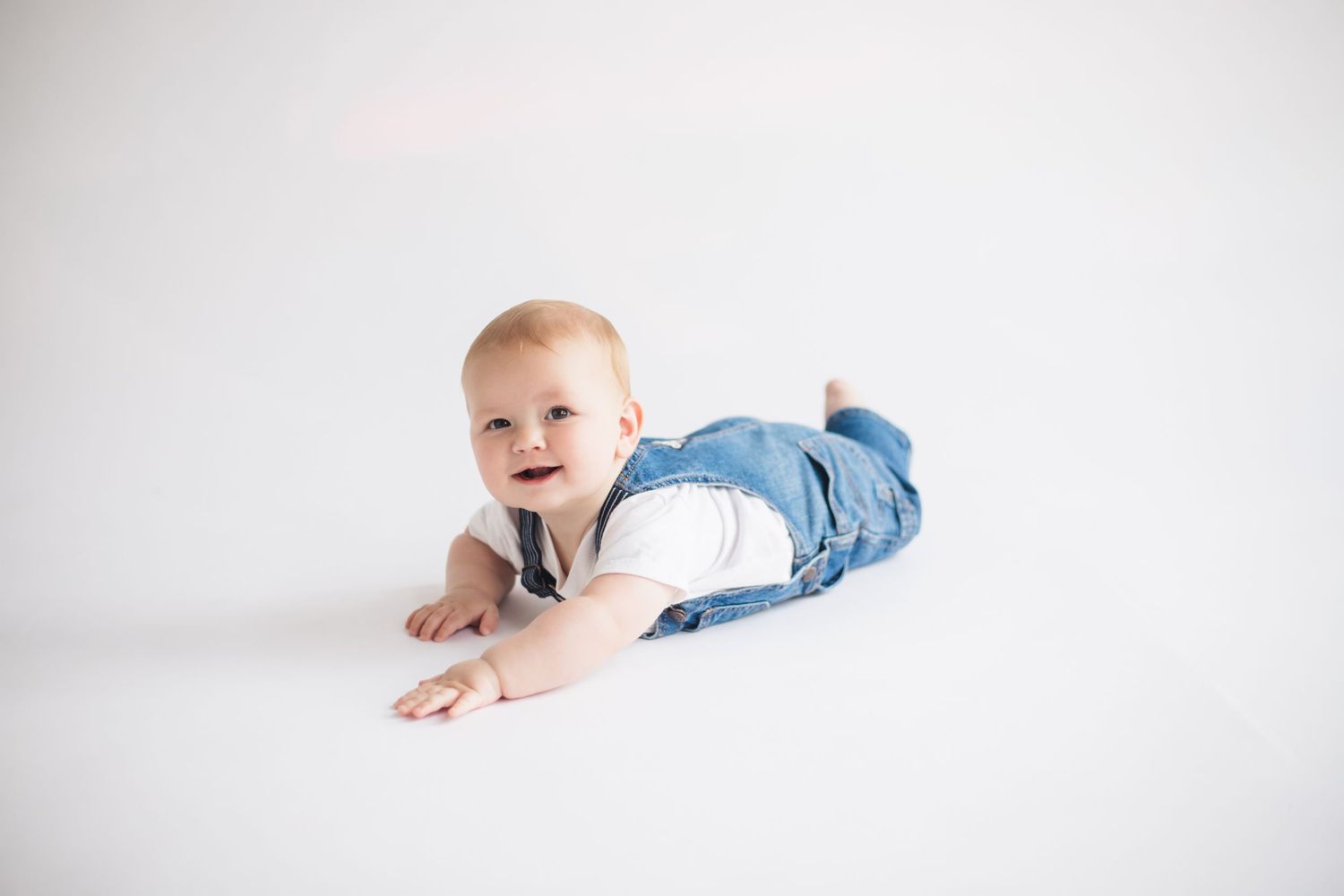 Baby crawling on white background during minimalist photo session.