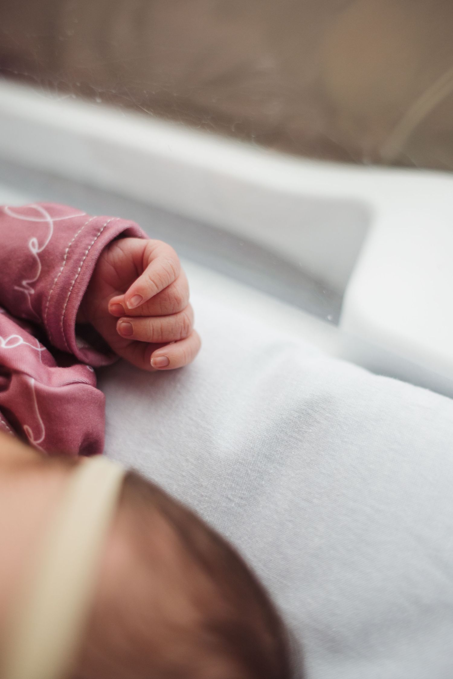 A close-up of small hands grasping soft pink fabric against a white background.