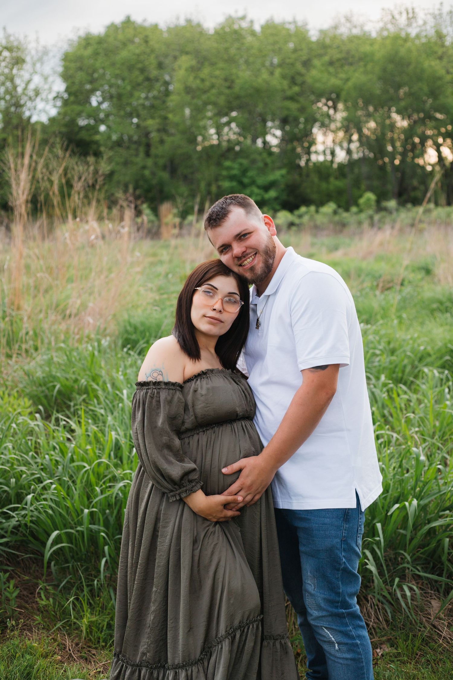 Tender outdoor maternity photoshoot in nature with couple embracing.