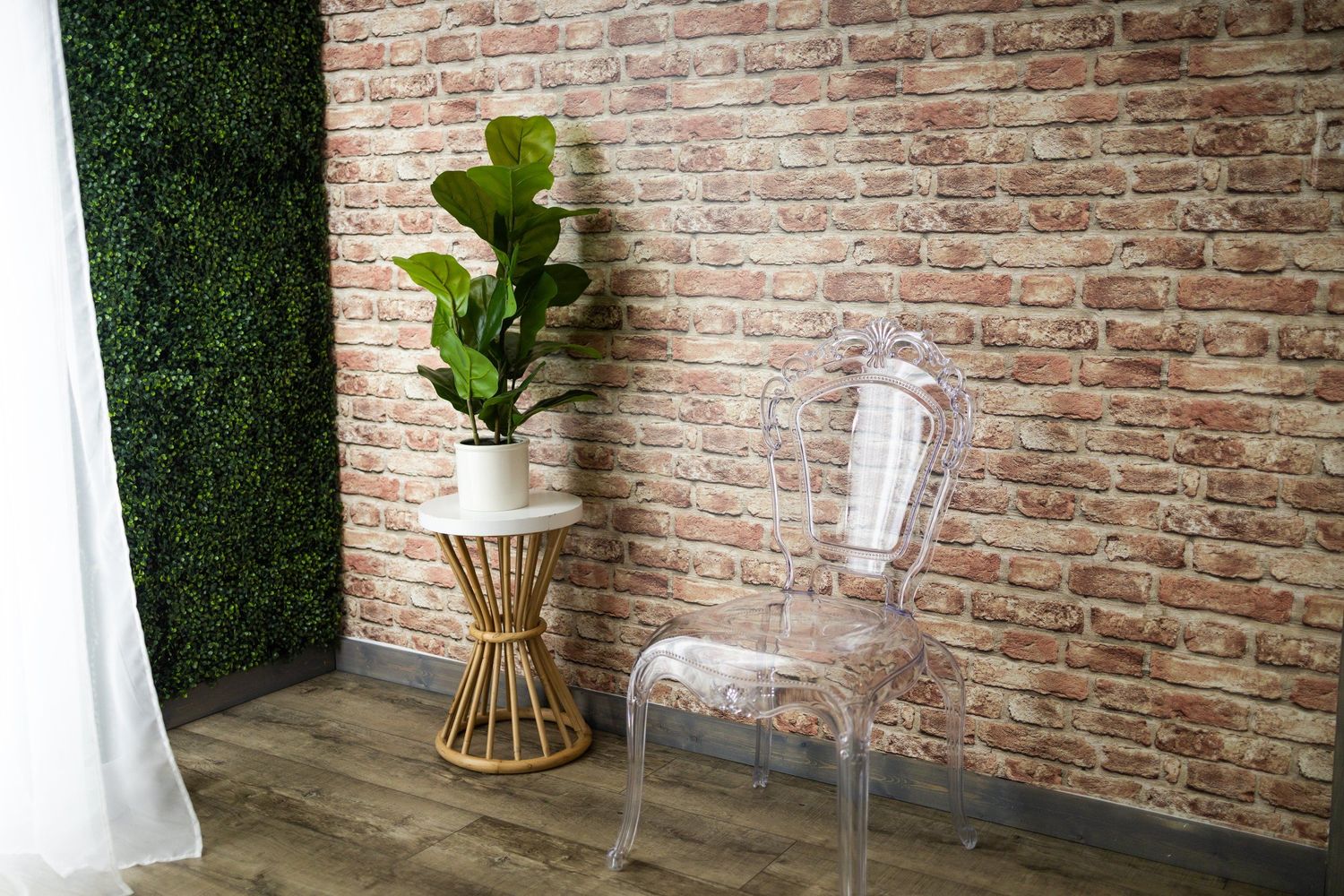 Modern interior with exposed brick wall, ghost chair, and decorative fiddle leaf fig plant.