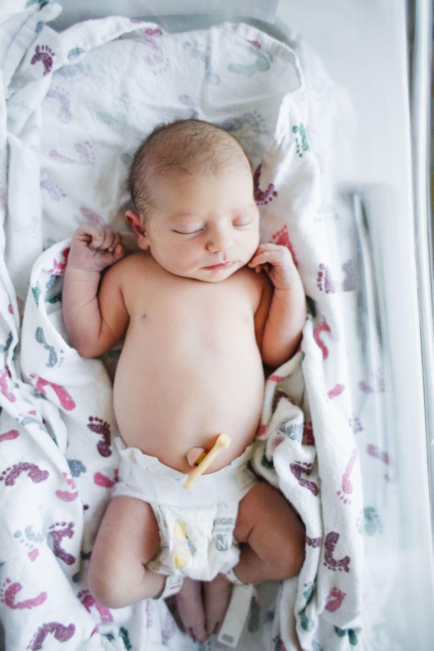 A newborn baby lies peacefully on white bedding patterned with pink and purple butterflies in four similar poses.