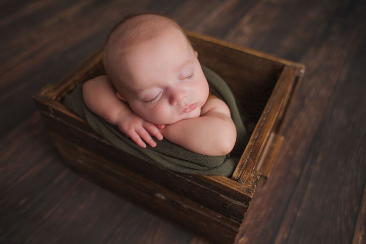 side profile of sleeping newborn baby in blue wrap in basket