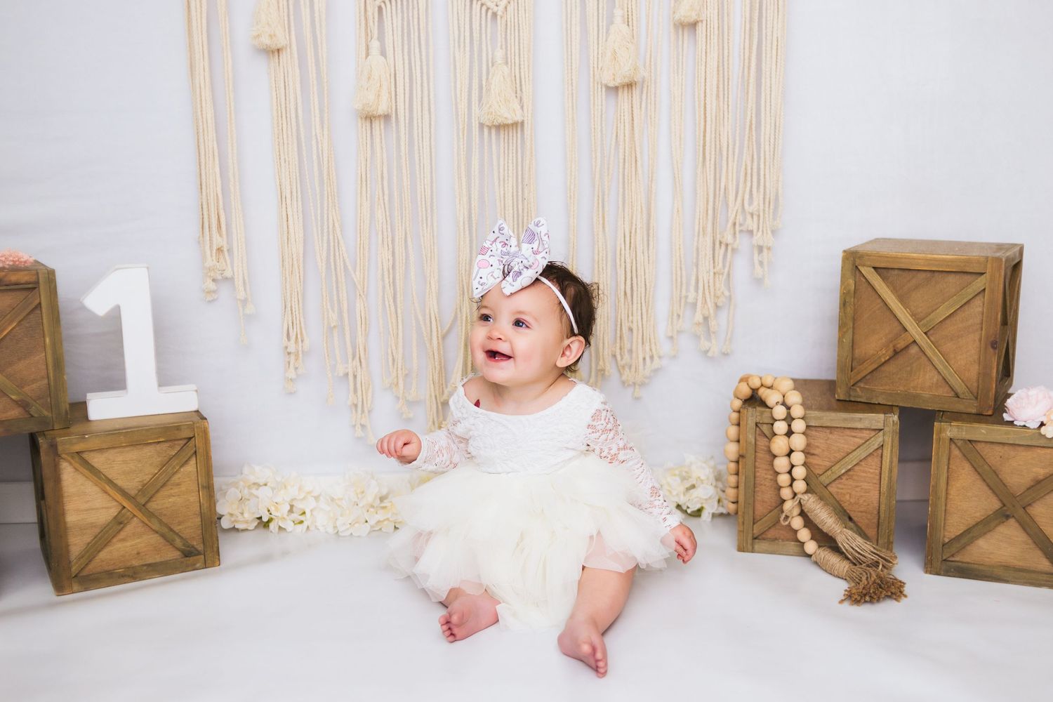 Birthday celebration setup with macrame backdrop, wooden crates, and gold accents.