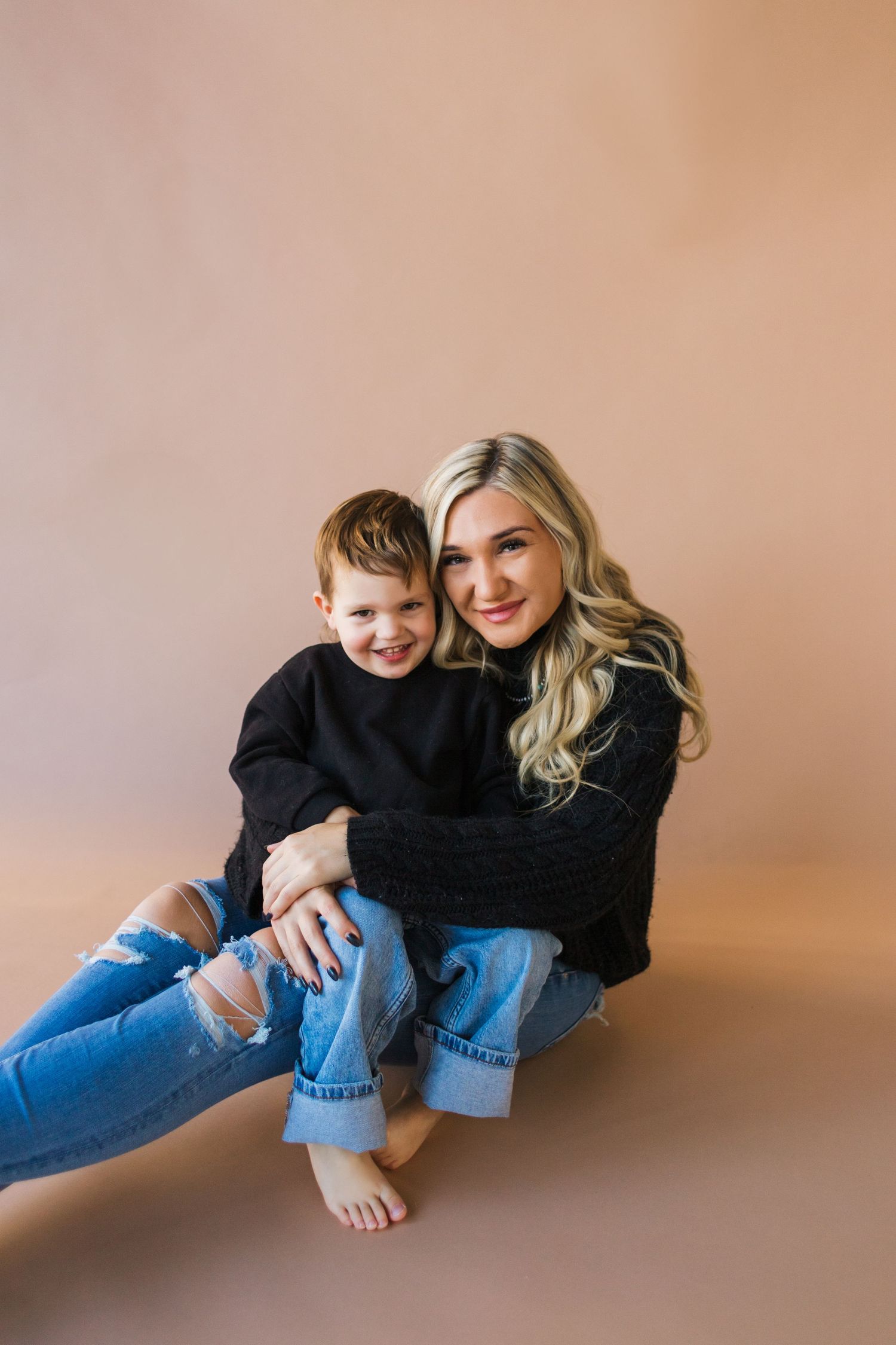 Parent and child share playful moments on brown studio background.