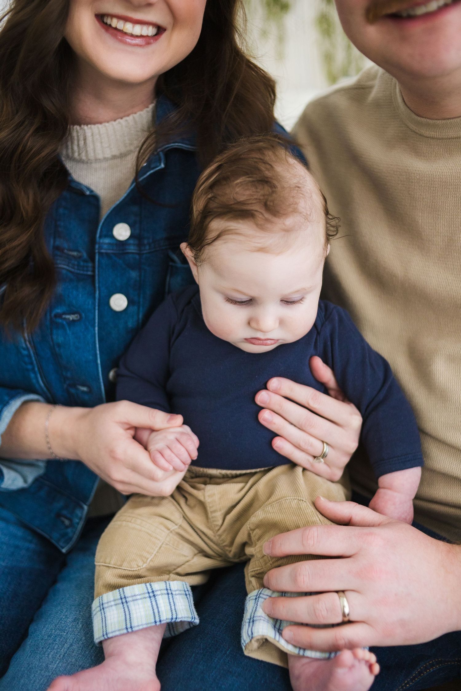 Intimate family portrait session with parents holding baby in casual outfits.