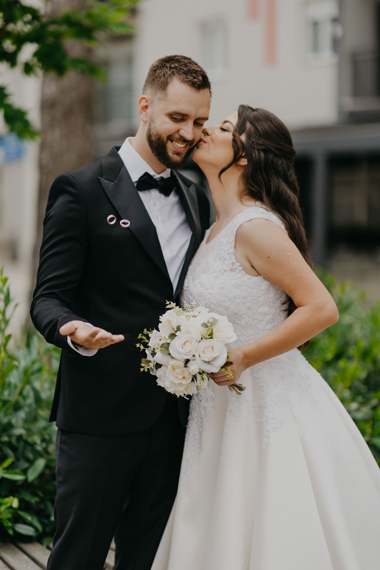 A couple shares a romantic moment in wedding attire while holding a white floral bouquet on their special day.