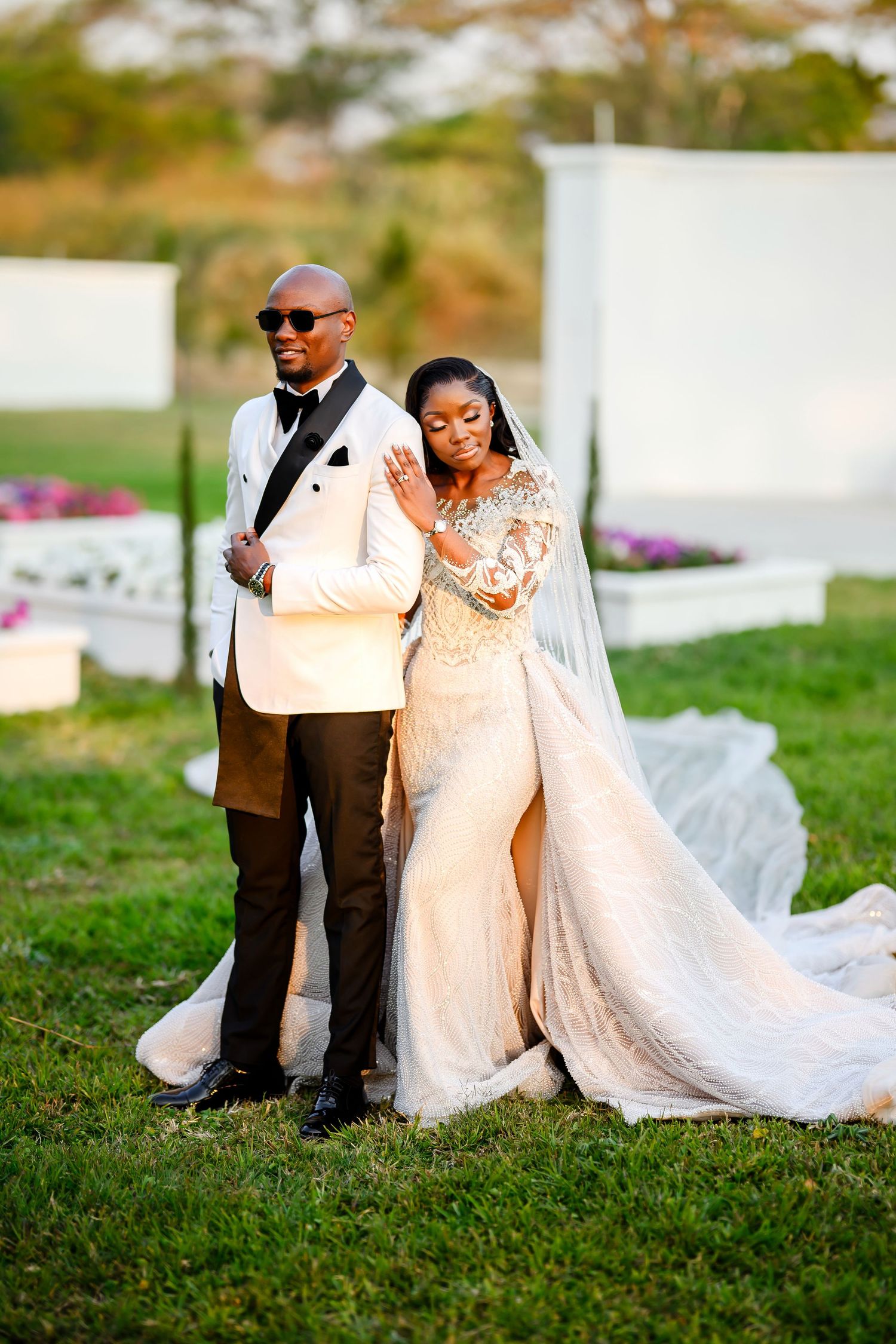A romantic wedding couple shares intimate moments on a grassy lawn during their outdoor celebration.