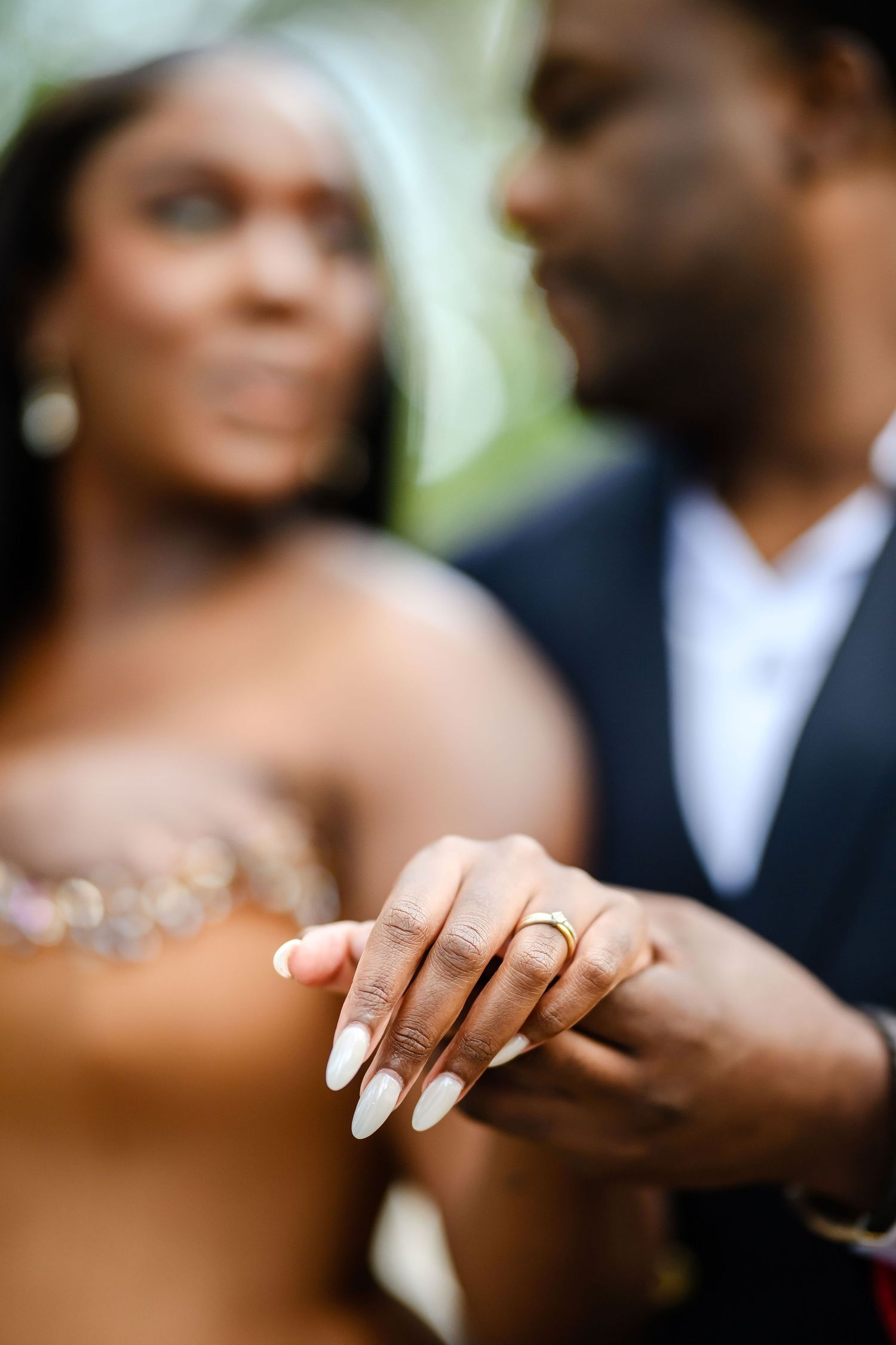 Close up of elegant manicured hands with a wedding ring showing against a soft focused background during romantic moment.