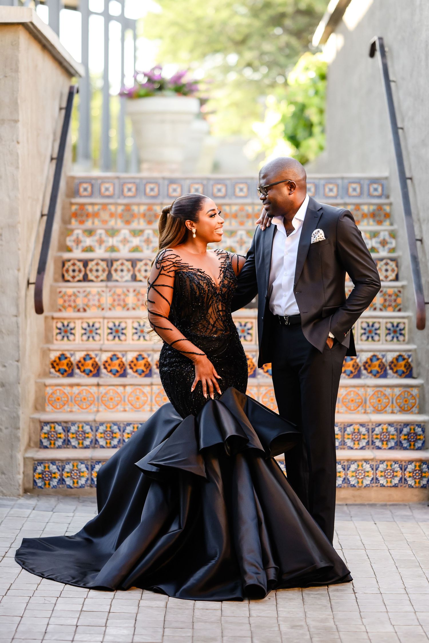 Glamorous couple in formal wear posing on decorative tiled stairs during an engagement photo session at Droombos