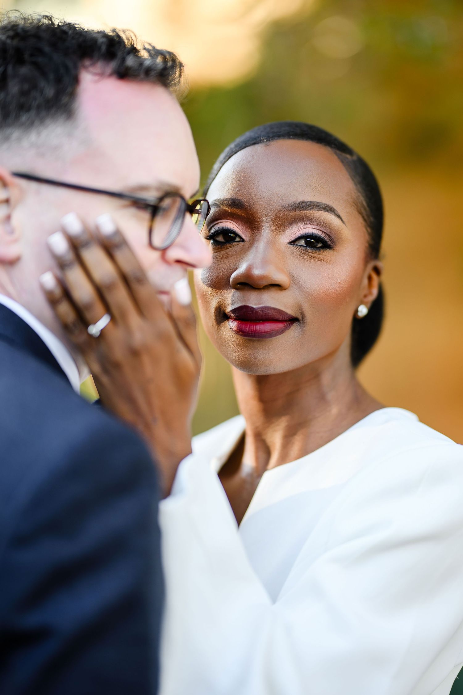 Close-up portrait of a couple sharing an intimate moment outdoors in formal attire.