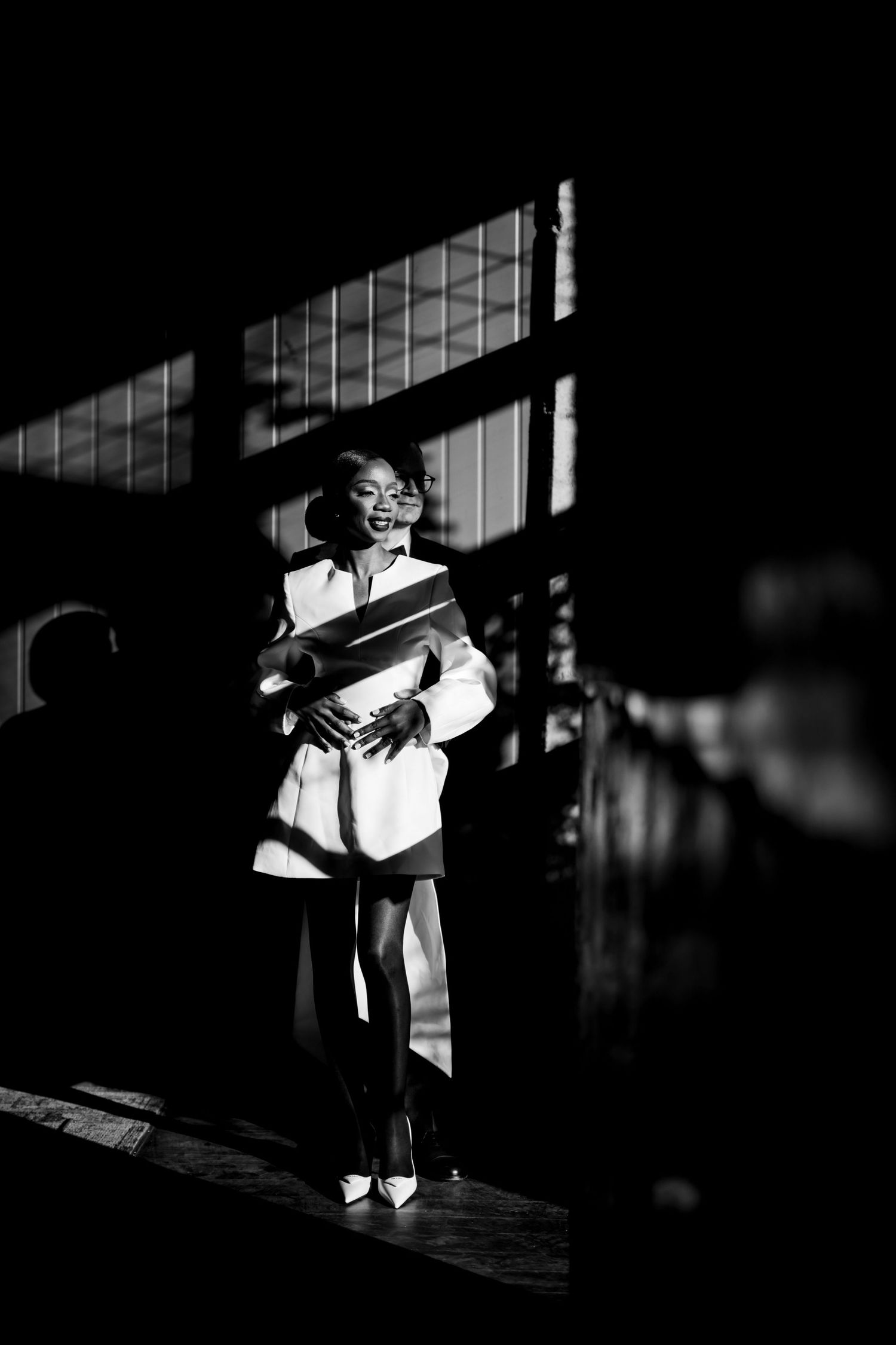 A vintage black and white photograph of someone holding books while standing in dramatic window lighting.