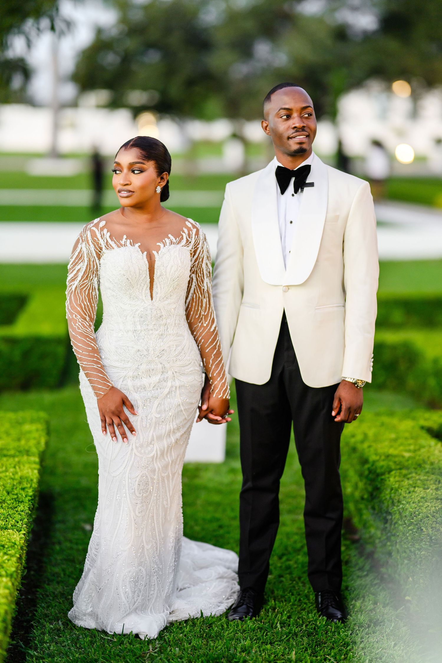 Newlyweds in elegant attire pose on manicured lawn during outdoor wedding photoshoot In Lusaka Zambia