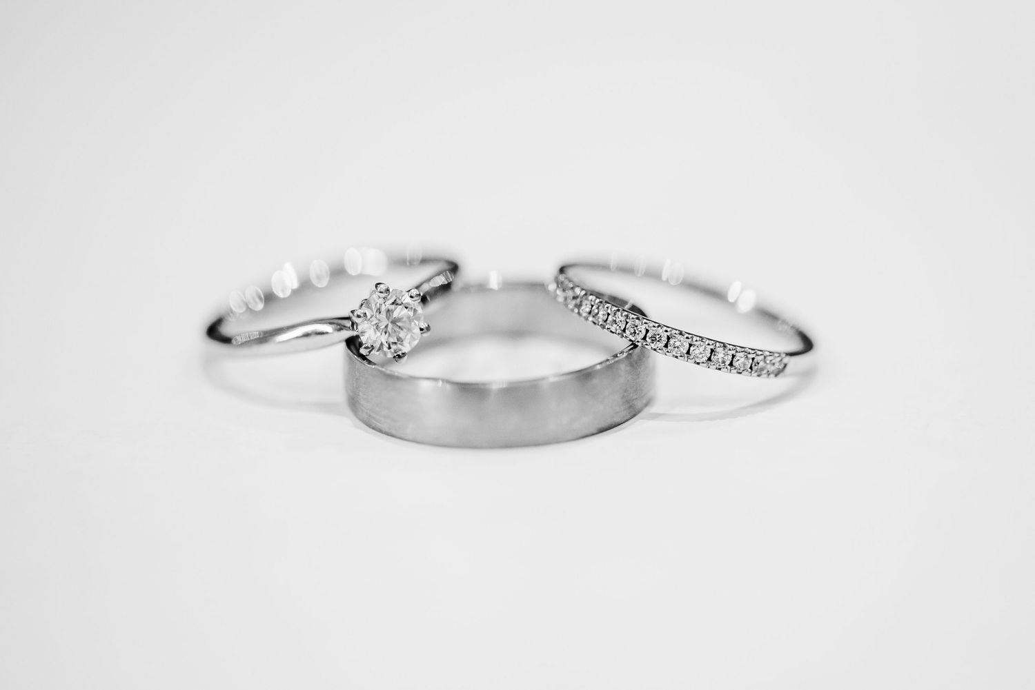 Three wedding rings arranged on white background showing engagement and wedding bands.