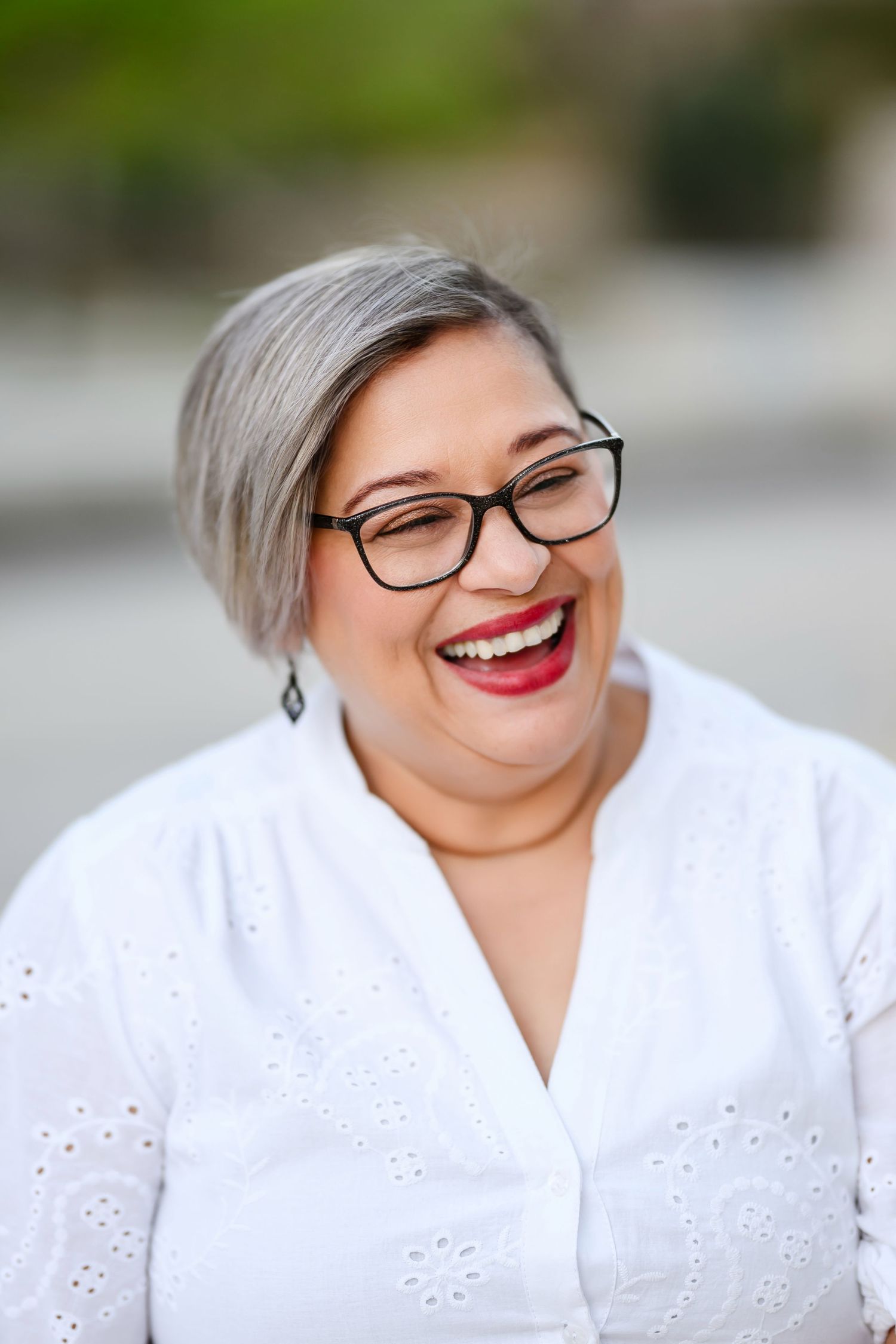 Portrait series showing joyful expressions in a white eyelet lace top with black-framed glasses and bright red lipstick.